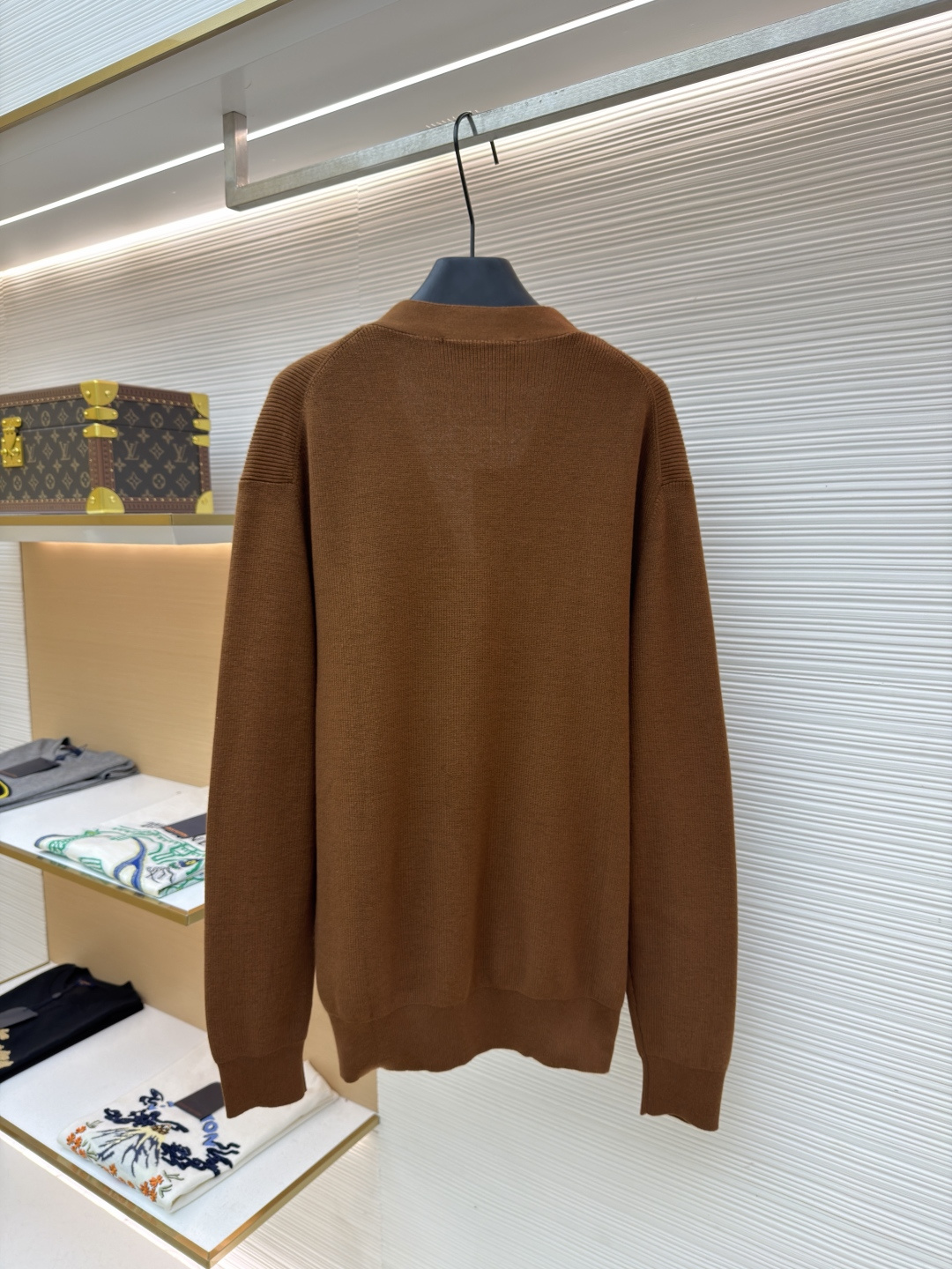 p400 LOUIS VUITTON 字母徽章标识针织V领开衫毛衣
●面料：羊毛面料
●工艺：针织制作
●颜色：棕色
●版型：合身版型
●克重：约535克
●尺码：S-M-L-XL
●描述：这款焦糖棕V领开衫采用高支数羊毛混纺针织面料，经双股线精密织造，兼具保暖性与透气性，表面纹理细腻且抗起球性能优异，色牢度达4.5级以上，久穿不易褪色变形。V领采用包边嵌条工艺，领口挺括不易变形；门襟选用四颗哑光质感的定制金属纽扣，扣眼采用加固锁边工艺，耐用性更强。衣身两侧嵌缝立体贴袋，袋口做双针明线加固，兼具实用性与美观度；袖口及下摆采用罗纹收边，弹力适中贴合身形且不易松弛。成衣经过整烫定型、线头修剪等多道后整理工序，针脚均匀细密，走线流畅无跳线，整体版型宽松有度，日常穿搭舒适随性，适配多种风格场景。整体走线平直细腻，面料舒适柔软，颜色一致无色差 能与同款搭配营造时尚造型，驾驭各种场合，定制辅料，三标齐全，男女同款！
