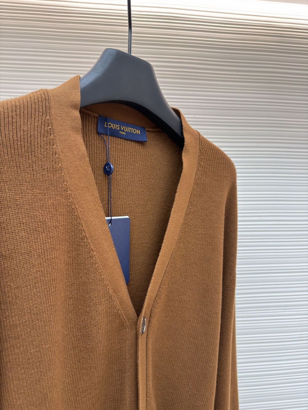 p400 LOUIS VUITTON 字母徽章标识针织V领开衫毛衣
●面料：羊毛面料
●工艺：针织制作
●颜色：棕色
●版型：合身版型
●克重：约535克
●尺码：S-M-L-XL
●描述：这款焦糖棕V领开衫采用高支数羊毛混纺针织面料，经双股线精密织造，兼具保暖性与透气性，表面纹理细腻且抗起球性能优异，色牢度达4.5级以上，久穿不易褪色变形。V领采用包边嵌条工艺，领口挺括不易变形；门襟选用四颗哑光质感的定制金属纽扣，扣眼采用加固锁边工艺，耐用性更强。衣身两侧嵌缝立体贴袋，袋口做双针明线加固，兼具实用性与美观度；袖口及下摆采用罗纹收边，弹力适中贴合身形且不易松弛。成衣经过整烫定型、线头修剪等多道后整理工序，针脚均匀细密，走线流畅无跳线，整体版型宽松有度，日常穿搭舒适随性，适配多种风格场景。整体走线平直细腻，面料舒适柔软，颜色一致无色差 能与同款搭配营造时尚造型，驾驭各种场合，定制辅料，三标齐全，男女同款！