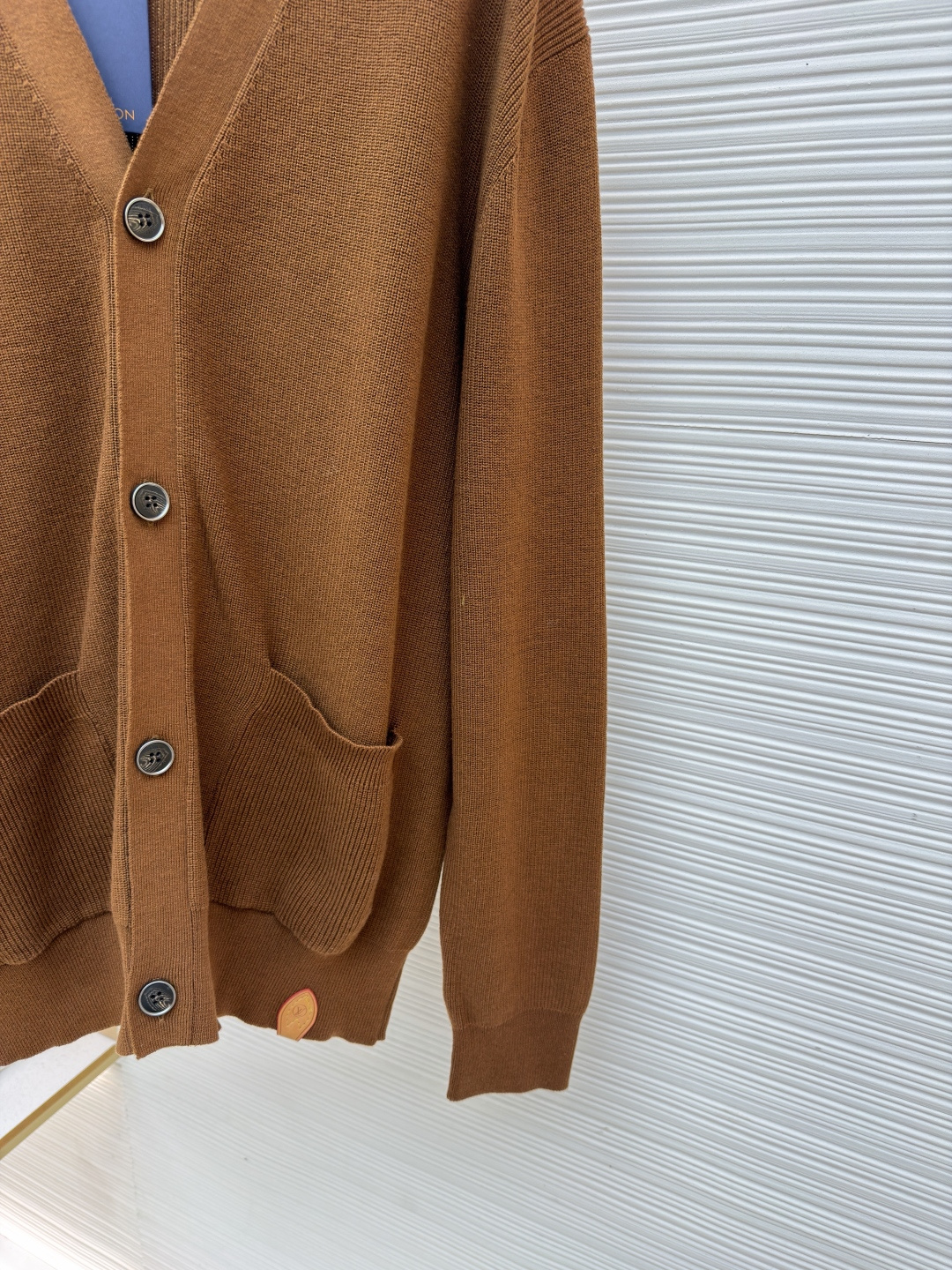 p400 LOUIS VUITTON 字母徽章标识针织V领开衫毛衣
●面料：羊毛面料
●工艺：针织制作
●颜色：棕色
●版型：合身版型
●克重：约535克
●尺码：S-M-L-XL
●描述：这款焦糖棕V领开衫采用高支数羊毛混纺针织面料，经双股线精密织造，兼具保暖性与透气性，表面纹理细腻且抗起球性能优异，色牢度达4.5级以上，久穿不易褪色变形。V领采用包边嵌条工艺，领口挺括不易变形；门襟选用四颗哑光质感的定制金属纽扣，扣眼采用加固锁边工艺，耐用性更强。衣身两侧嵌缝立体贴袋，袋口做双针明线加固，兼具实用性与美观度；袖口及下摆采用罗纹收边，弹力适中贴合身形且不易松弛。成衣经过整烫定型、线头修剪等多道后整理工序，针脚均匀细密，走线流畅无跳线，整体版型宽松有度，日常穿搭舒适随性，适配多种风格场景。整体走线平直细腻，面料舒适柔软，颜色一致无色差 能与同款搭配营造时尚造型，驾驭各种场合，定制辅料，三标齐全，男女同款！