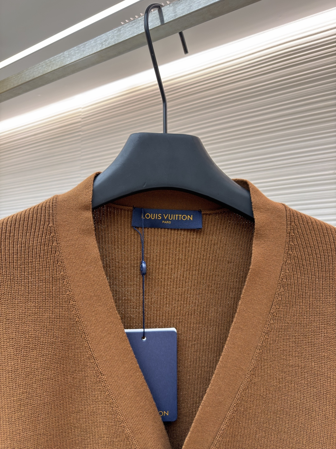 p400 LOUIS VUITTON 字母徽章标识针织V领开衫毛衣
●面料：羊毛面料
●工艺：针织制作
●颜色：棕色
●版型：合身版型
●克重：约535克
●尺码：S-M-L-XL
●描述：这款焦糖棕V领开衫采用高支数羊毛混纺针织面料，经双股线精密织造，兼具保暖性与透气性，表面纹理细腻且抗起球性能优异，色牢度达4.5级以上，久穿不易褪色变形。V领采用包边嵌条工艺，领口挺括不易变形；门襟选用四颗哑光质感的定制金属纽扣，扣眼采用加固锁边工艺，耐用性更强。衣身两侧嵌缝立体贴袋，袋口做双针明线加固，兼具实用性与美观度；袖口及下摆采用罗纹收边，弹力适中贴合身形且不易松弛。成衣经过整烫定型、线头修剪等多道后整理工序，针脚均匀细密，走线流畅无跳线，整体版型宽松有度，日常穿搭舒适随性，适配多种风格场景。整体走线平直细腻，面料舒适柔软，颜色一致无色差 能与同款搭配营造时尚造型，驾驭各种场合，定制辅料，三标齐全，男女同款！
