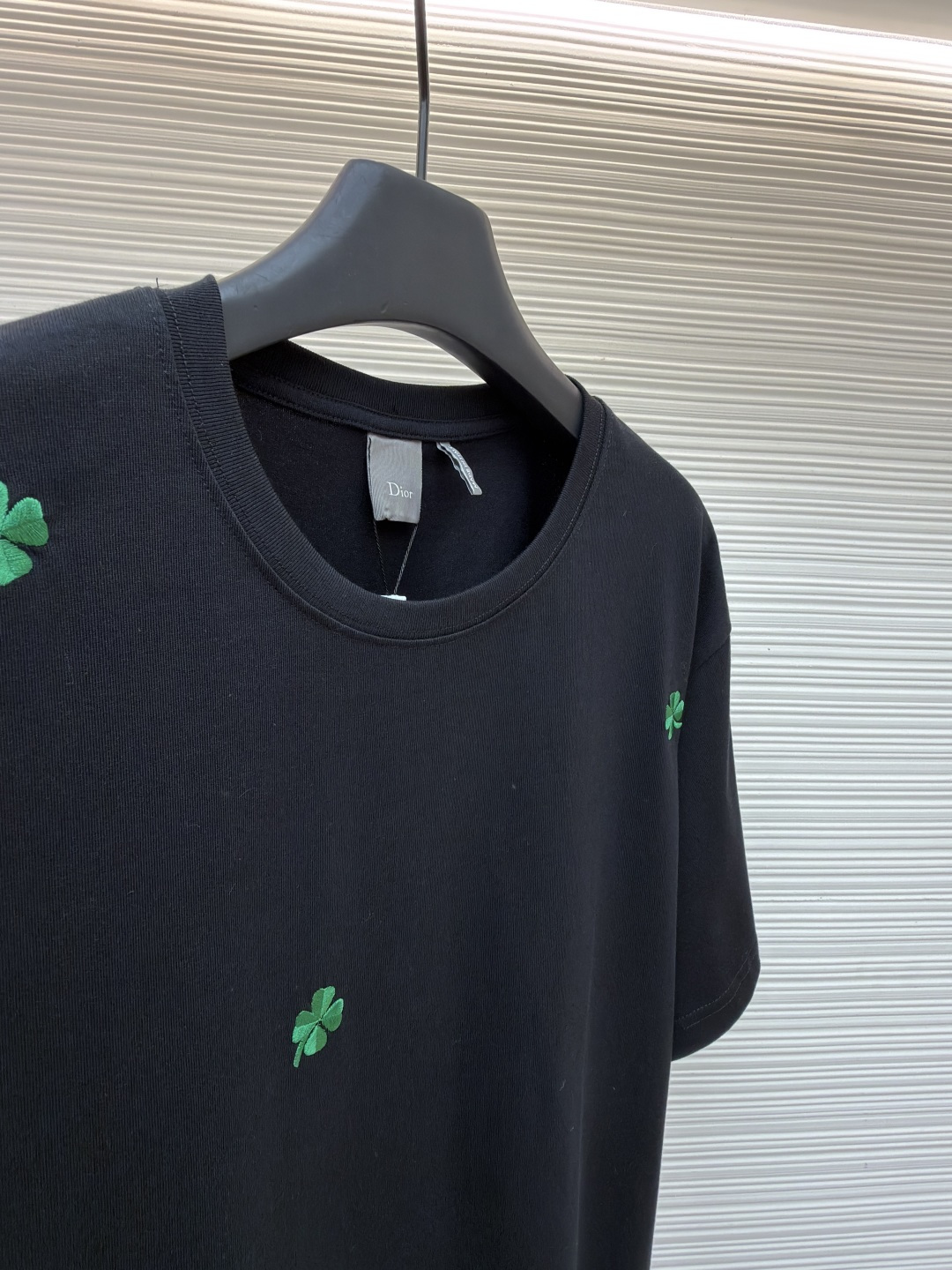 p225 Dior 棉质宽松圆领四叶草刺绣图案T恤
●原版：12000购入开发
●面料：精梳棉面料
●工艺：刺绣制作
●颜色：黑色
●版型：合身版型
●克重：约345克
●尺码：S-M-L-XL
●描述：这款黑色短袖T恤采用高支双股精梳棉混纺面料，经预缩与抗起球处理，触感柔软亲肤，透气吸汗且不易变形起球，色牢度达4级以上，久洗不易褪色发白。领口采用高弹力罗纹搭配三本针包边工艺，反复穿着不易松弛卷边；衣身侧缝采用双针埋夹工艺，走线平整牢固，减少皮肤摩擦感。衣身分布的绿色三叶草图案采用精密刺绣工艺，针脚细密均匀，图案立体饱满且不易脱线；右下角品牌标识采用精细胶印工艺，附着力强不易脱落。成衣经过验针、整烫、去污等多道质检工序，版型宽松有度，适配日常休闲、约会出游等多种场景，兼具精致细节与实穿性。整体走线平直细腻，面料舒适柔软，颜色一致无色差 能与同款搭配营造时尚造型，驾驭各种场合，定制辅料，三标齐全，男女同款！