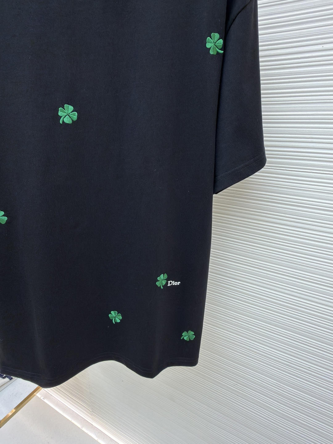 p225 Dior 棉质宽松圆领四叶草刺绣图案T恤
●原版：12000购入开发
●面料：精梳棉面料
●工艺：刺绣制作
●颜色：黑色
●版型：合身版型
●克重：约345克
●尺码：S-M-L-XL
●描述：这款黑色短袖T恤采用高支双股精梳棉混纺面料，经预缩与抗起球处理，触感柔软亲肤，透气吸汗且不易变形起球，色牢度达4级以上，久洗不易褪色发白。领口采用高弹力罗纹搭配三本针包边工艺，反复穿着不易松弛卷边；衣身侧缝采用双针埋夹工艺，走线平整牢固，减少皮肤摩擦感。衣身分布的绿色三叶草图案采用精密刺绣工艺，针脚细密均匀，图案立体饱满且不易脱线；右下角品牌标识采用精细胶印工艺，附着力强不易脱落。成衣经过验针、整烫、去污等多道质检工序，版型宽松有度，适配日常休闲、约会出游等多种场景，兼具精致细节与实穿性。整体走线平直细腻，面料舒适柔软，颜色一致无色差 能与同款搭配营造时尚造型，驾驭各种场合，定制辅料，三标齐全，男女同款！