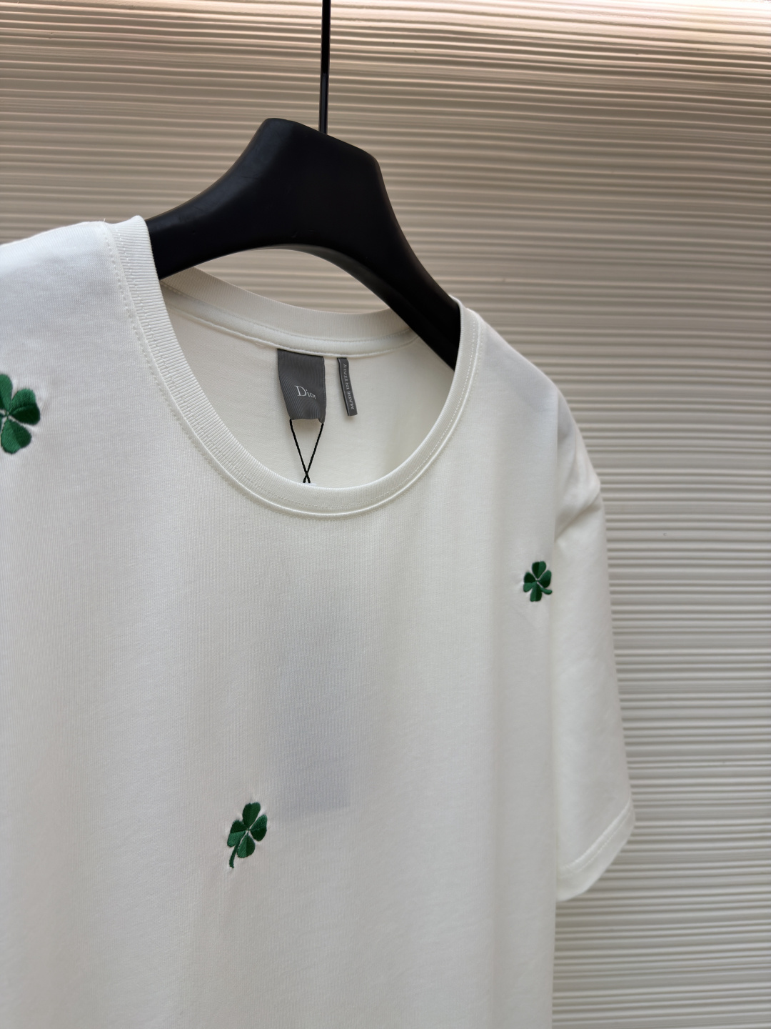 p225 Dior 棉质宽松圆领四叶草刺绣图案T恤
●原版：12000购入开发
●面料：精梳棉面料
●工艺：刺绣制作
●颜色：白色
●版型：合身版型
●克重：约335克
●尺码：S-M-L-XL
●描述：这款黑色短袖T恤采用高支双股精梳棉混纺面料，经预缩与抗起球处理，触感柔软亲肤，透气吸汗且不易变形起球，色牢度达4级以上，久洗不易褪色发白。领口采用高弹力罗纹搭配三本针包边工艺，反复穿着不易松弛卷边；衣身侧缝采用双针埋夹工艺，走线平整牢固，减少皮肤摩擦感。衣身分布的绿色三叶草图案采用精密刺绣工艺，针脚细密均匀，图案立体饱满且不易脱线；右下角品牌标识采用精细胶印工艺，附着力强不易脱落。成衣经过验针、整烫、去污等多道质检工序，版型宽松有度，适配日常休闲、约会出游等多种场景，兼具精致细节与实穿性。整体走线平直细腻，面料舒适柔软，颜色一致无色差 能与同款搭配营造时尚造型，驾驭各种场合，定制辅料，三标齐全，男女同款！