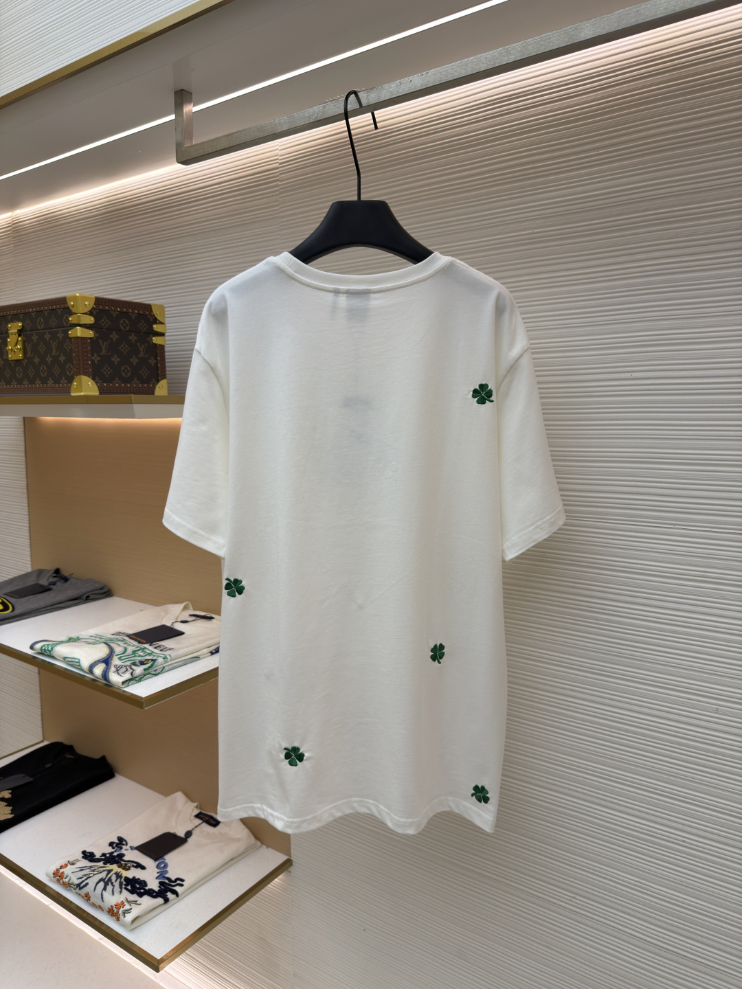 p225 Dior 棉质宽松圆领四叶草刺绣图案T恤
●原版：12000购入开发
●面料：精梳棉面料
●工艺：刺绣制作
●颜色：白色
●版型：合身版型
●克重：约335克
●尺码：S-M-L-XL
●描述：这款黑色短袖T恤采用高支双股精梳棉混纺面料，经预缩与抗起球处理，触感柔软亲肤，透气吸汗且不易变形起球，色牢度达4级以上，久洗不易褪色发白。领口采用高弹力罗纹搭配三本针包边工艺，反复穿着不易松弛卷边；衣身侧缝采用双针埋夹工艺，走线平整牢固，减少皮肤摩擦感。衣身分布的绿色三叶草图案采用精密刺绣工艺，针脚细密均匀，图案立体饱满且不易脱线；右下角品牌标识采用精细胶印工艺，附着力强不易脱落。成衣经过验针、整烫、去污等多道质检工序，版型宽松有度，适配日常休闲、约会出游等多种场景，兼具精致细节与实穿性。整体走线平直细腻，面料舒适柔软，颜色一致无色差 能与同款搭配营造时尚造型，驾驭各种场合，定制辅料，三标齐全，男女同款！