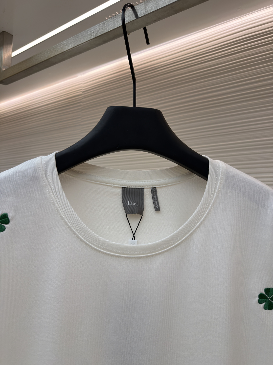 p225 Dior 棉质宽松圆领四叶草刺绣图案T恤
●原版：12000购入开发
●面料：精梳棉面料
●工艺：刺绣制作
●颜色：白色
●版型：合身版型
●克重：约335克
●尺码：S-M-L-XL
●描述：这款黑色短袖T恤采用高支双股精梳棉混纺面料，经预缩与抗起球处理，触感柔软亲肤，透气吸汗且不易变形起球，色牢度达4级以上，久洗不易褪色发白。领口采用高弹力罗纹搭配三本针包边工艺，反复穿着不易松弛卷边；衣身侧缝采用双针埋夹工艺，走线平整牢固，减少皮肤摩擦感。衣身分布的绿色三叶草图案采用精密刺绣工艺，针脚细密均匀，图案立体饱满且不易脱线；右下角品牌标识采用精细胶印工艺，附着力强不易脱落。成衣经过验针、整烫、去污等多道质检工序，版型宽松有度，适配日常休闲、约会出游等多种场景，兼具精致细节与实穿性。整体走线平直细腻，面料舒适柔软，颜色一致无色差 能与同款搭配营造时尚造型，驾驭各种场合，定制辅料，三标齐全，男女同款！