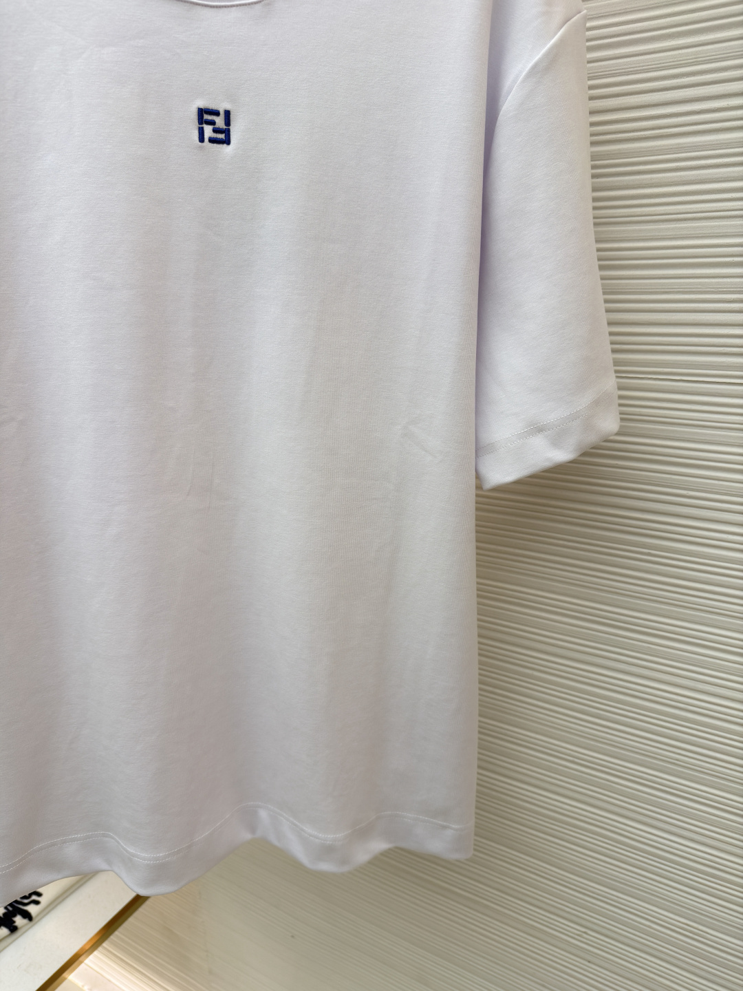 p230 Fendi 米粒刺绣圆领短袖
●原版：5800购入开发
●面料：平纹针织面料
●工艺：刺绣制作
●颜色：白色
●版型：合身版型
●克重：约385克
●尺码：XS-S-M-L
●描述：采用24支双面棉质针织面料，克重为270g/㎡。24支属于中支数，赋予面料适中的厚度和良好的耐用性。双面结构面料正反面质感一致，质地均匀、平整且具有一定的弹性和挺括度。克重属于重磅级别，这确保具有优异的挺括感、垂坠感和抗皱性，成衣廓形饱满不易软塌。指使用平针针法通过高密度、平行排列的直线针脚来填充图案区域。其作用是形成光滑、平整、饱满的绣面，色彩均匀，覆盖力强。通过增加绣线层数在刺绣时使用较粗的绣线实现，使图案明显凸出于面料表面，形成触手可及的浮雕感。整体走线平直细腻，面料舒适柔软，颜色一致无色差 能与同款搭配营造时尚造型，驾驭各种场合，定制辅料，三标齐全，男女同款！