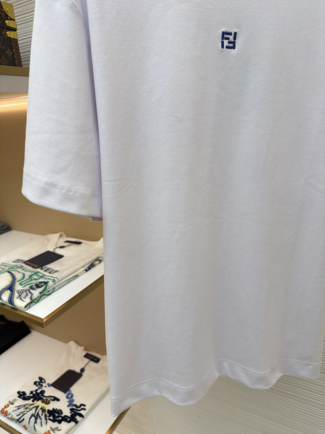 p230 Fendi 米粒刺绣圆领短袖
●原版：5800购入开发
●面料：平纹针织面料
●工艺：刺绣制作
●颜色：白色
●版型：合身版型
●克重：约385克
●尺码：XS-S-M-L
●描述：采用24支双面棉质针织面料，克重为270g/㎡。24支属于中支数，赋予面料适中的厚度和良好的耐用性。双面结构面料正反面质感一致，质地均匀、平整且具有一定的弹性和挺括度。克重属于重磅级别，这确保具有优异的挺括感、垂坠感和抗皱性，成衣廓形饱满不易软塌。指使用平针针法通过高密度、平行排列的直线针脚来填充图案区域。其作用是形成光滑、平整、饱满的绣面，色彩均匀，覆盖力强。通过增加绣线层数在刺绣时使用较粗的绣线实现，使图案明显凸出于面料表面，形成触手可及的浮雕感。整体走线平直细腻，面料舒适柔软，颜色一致无色差 能与同款搭配营造时尚造型，驾驭各种场合，定制辅料，三标齐全，男女同款！