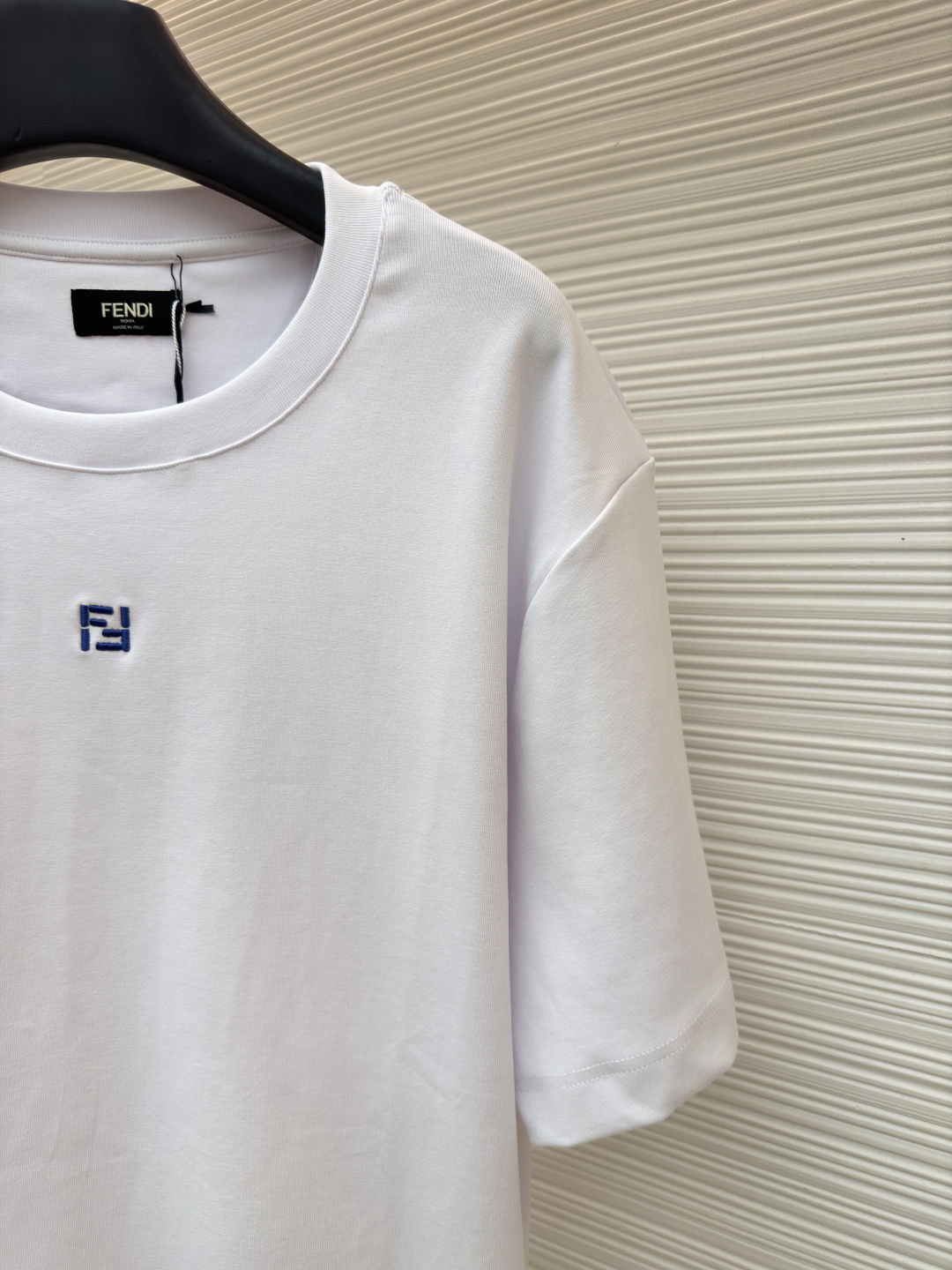 p230 Fendi 米粒刺绣圆领短袖
●原版：5800购入开发
●面料：平纹针织面料
●工艺：刺绣制作
●颜色：白色
●版型：合身版型
●克重：约385克
●尺码：XS-S-M-L
●描述：采用24支双面棉质针织面料，克重为270g/㎡。24支属于中支数，赋予面料适中的厚度和良好的耐用性。双面结构面料正反面质感一致，质地均匀、平整且具有一定的弹性和挺括度。克重属于重磅级别，这确保具有优异的挺括感、垂坠感和抗皱性，成衣廓形饱满不易软塌。指使用平针针法通过高密度、平行排列的直线针脚来填充图案区域。其作用是形成光滑、平整、饱满的绣面，色彩均匀，覆盖力强。通过增加绣线层数在刺绣时使用较粗的绣线实现，使图案明显凸出于面料表面，形成触手可及的浮雕感。整体走线平直细腻，面料舒适柔软，颜色一致无色差 能与同款搭配营造时尚造型，驾驭各种场合，定制辅料，三标齐全，男女同款！