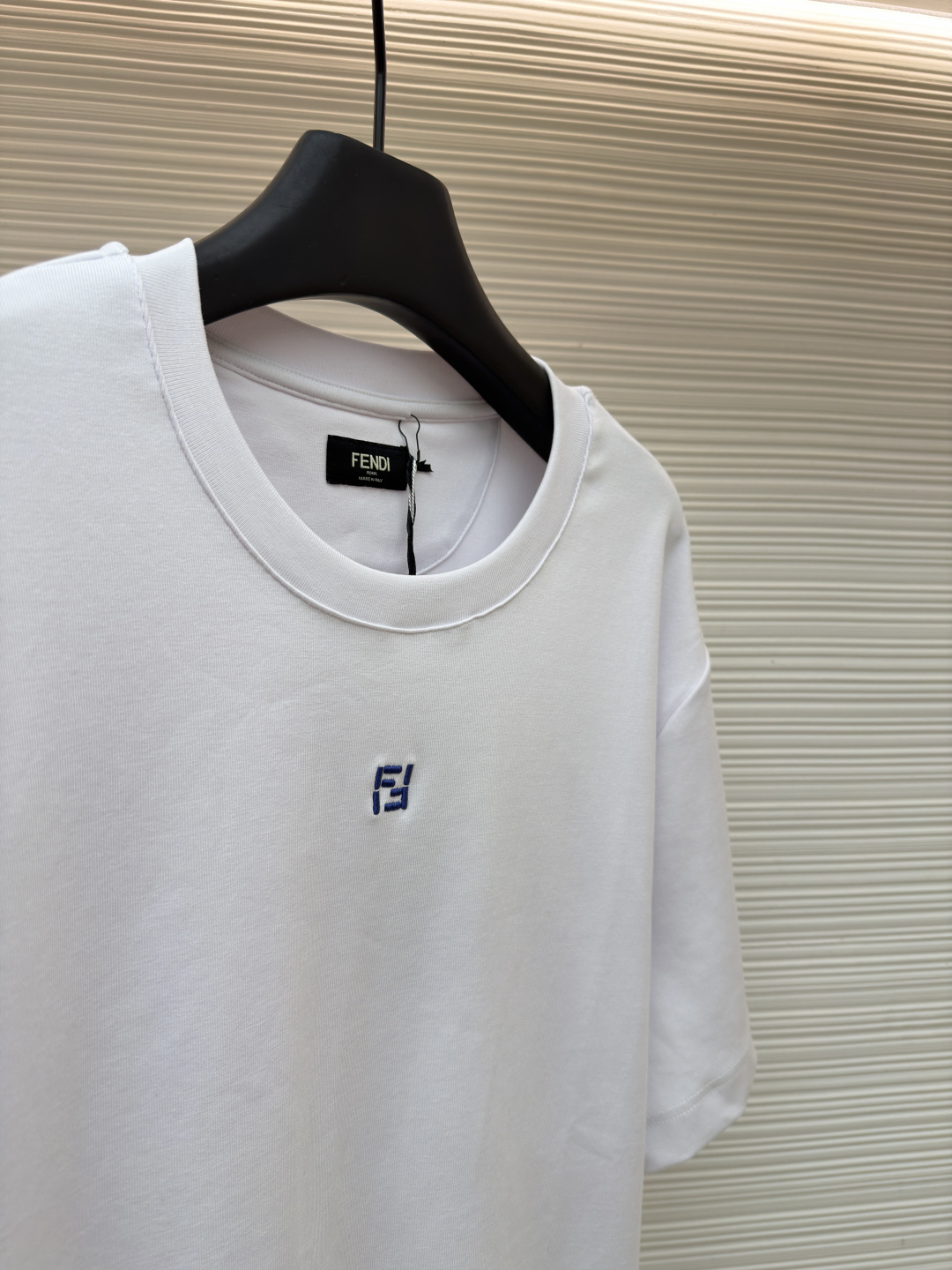 p230 Fendi 米粒刺绣圆领短袖
●原版：5800购入开发
●面料：平纹针织面料
●工艺：刺绣制作
●颜色：白色
●版型：合身版型
●克重：约385克
●尺码：XS-S-M-L
●描述：采用24支双面棉质针织面料，克重为270g/㎡。24支属于中支数，赋予面料适中的厚度和良好的耐用性。双面结构面料正反面质感一致，质地均匀、平整且具有一定的弹性和挺括度。克重属于重磅级别，这确保具有优异的挺括感、垂坠感和抗皱性，成衣廓形饱满不易软塌。指使用平针针法通过高密度、平行排列的直线针脚来填充图案区域。其作用是形成光滑、平整、饱满的绣面，色彩均匀，覆盖力强。通过增加绣线层数在刺绣时使用较粗的绣线实现，使图案明显凸出于面料表面，形成触手可及的浮雕感。整体走线平直细腻，面料舒适柔软，颜色一致无色差 能与同款搭配营造时尚造型，驾驭各种场合，定制辅料，三标齐全，男女同款！