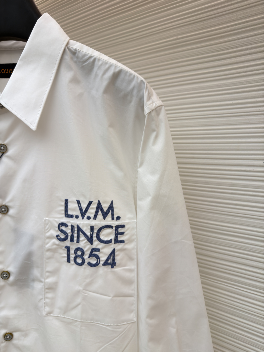 p365 LOUIS VUITTON 缎纹绣衬衫
●原版：10400购入开发
●面料：全棉面料
●工艺：刺绣制作
●颜色：白色
●版型：合身版型
●克重：约290克
●尺码：XS-S-M-L
●描述：本款由棉质府绸剪裁的挺括衬衫，因2026年春夏秀场的IVLegacy标识而更显精致。灵感源自路易威登个性化行李箱的历史，胸前口袋处印有模拟手绘效果的对比色LV.M.字母。本款多功能单品可搭配正式与日常造型。整体走线平直细腻，面料舒适柔软，颜色一致无色差 能与同款搭配营造时尚造型，驾驭各种场合，定制辅料，三标齐全，男女同款！