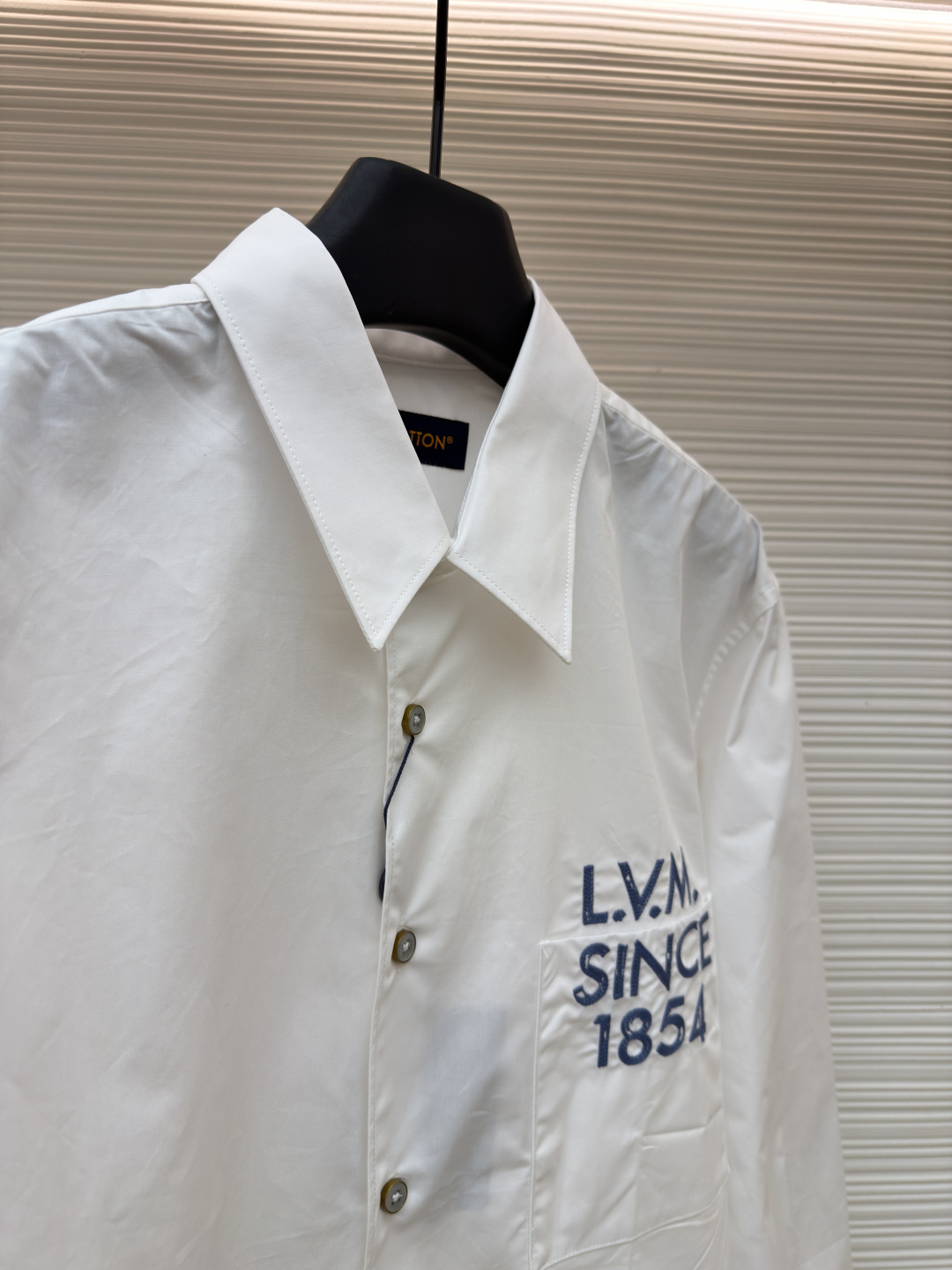 p365 LOUIS VUITTON 缎纹绣衬衫
●原版：10400购入开发
●面料：全棉面料
●工艺：刺绣制作
●颜色：白色
●版型：合身版型
●克重：约290克
●尺码：XS-S-M-L
●描述：本款由棉质府绸剪裁的挺括衬衫，因2026年春夏秀场的IVLegacy标识而更显精致。灵感源自路易威登个性化行李箱的历史，胸前口袋处印有模拟手绘效果的对比色LV.M.字母。本款多功能单品可搭配正式与日常造型。整体走线平直细腻，面料舒适柔软，颜色一致无色差 能与同款搭配营造时尚造型，驾驭各种场合，定制辅料，三标齐全，男女同款！