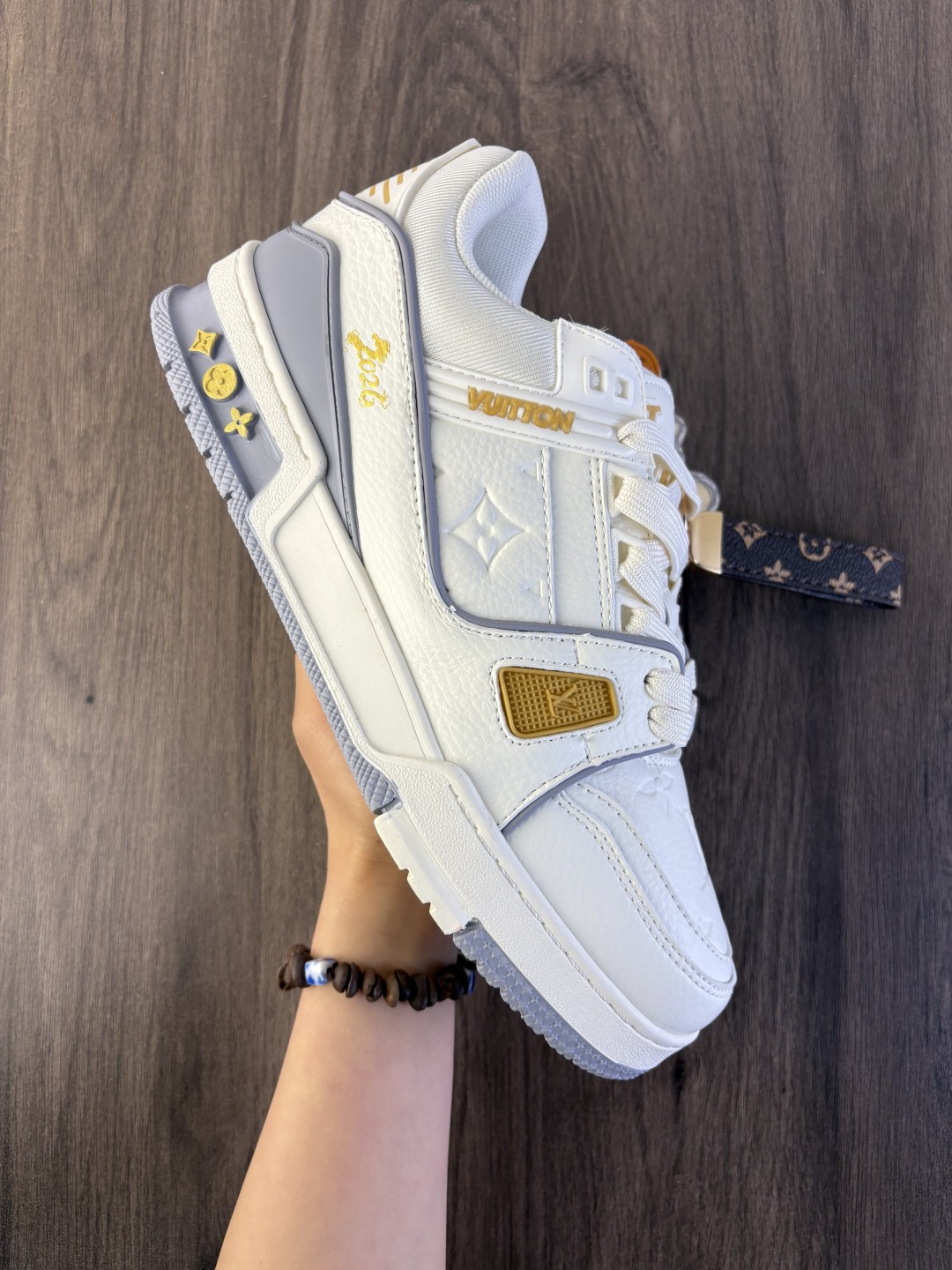 LV TRAINER迷彩马纹(中国红限定礼盒版本-钥匙扣丢失扣10元) 26年限定中国红礼盒及全套包装说明书防尘布袋物件,完美楦型,独家开模定制! trainer这个系列是路易威登融合街头潮流与高级时装的标志性之作.在材料选用上,鞋面采用Monogram印花与Monogram压纹粒面牛皮革的搭配,呈现出独特的复古韵味.荔枝纹粒面头层牛革鞋面,触感细腻且富有韧性,自带自然的皮革纹理,彰显高级质感,为鞋子增添了丰富的层次感.鞋垫采用原版超软乳胶材质,新鞋零磨合不磨脚,软乎乎的皮质包裹感超棒,鞋底则采用橡胶材质,刻有经典的Monogram花卉纹路,不仅防滑,还带走缓震效果还极具设计感.做工方面,TRAINER系列板鞋展现了精湛的工艺水准.鞋头采用圆润设计,原版空胶工艺搭配包边工艺,不仅美观,还能有效防踢蹭.鞋舌、侧面和后部饰有LV字母,侧面还有Vuitton标识,均做工精细,彰显品牌身份.鞋身走线工整均匀,看不到任何多余的线头,皮革的拼接处也处理得极为细腻,体现了我们对细节的极致追求.百搭属性直接封神!配牛仔裤是复古街头风,搭西装裤秒变松弛通勤感,甚至配半身裙都甜妹感拉满,堪称"衣柜万能钥匙".这双集颜值、质感、实穿性于一体的奢牌板鞋! 货号:2A8DM21VL IZE:36 37 38 39 40 41 42 43 44 45(不带半) 编码577