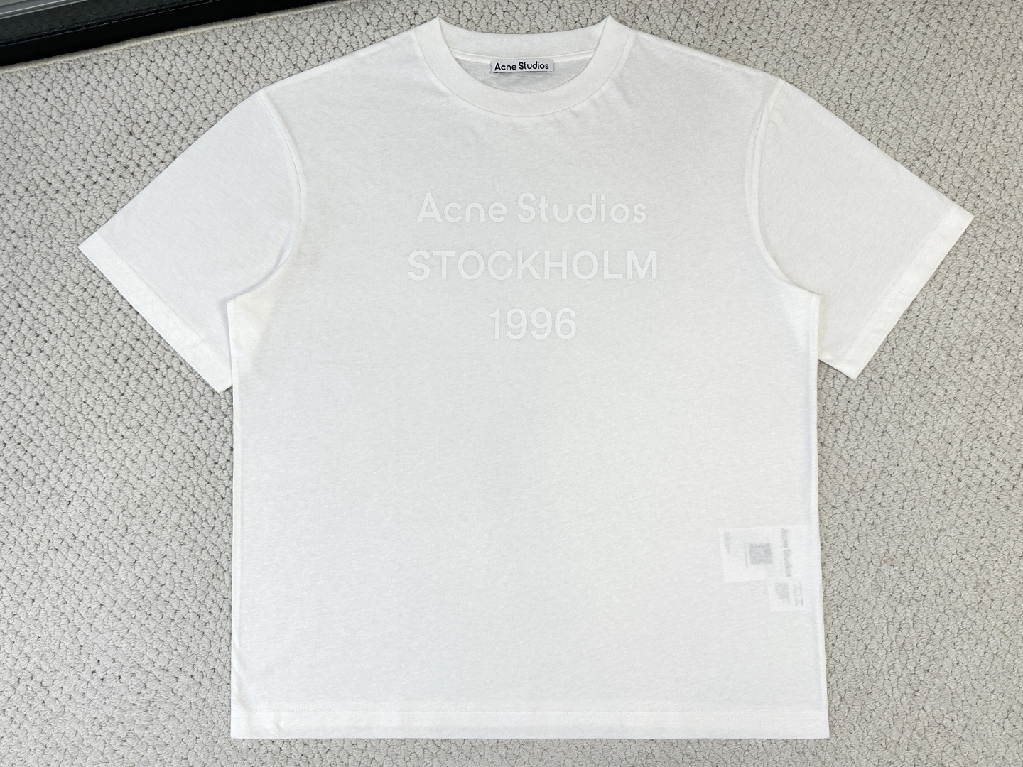 NO:956398,ACNE/ Product Introduction AC / Signet logo T-shirt Fabric 32 count cotton and linen blended jersey / 145G rib cotton and linen blended yarn rib / 145G This round neck T-shirt is made of cotton/linen blended jersey fabric, with an irregular texture effect on the surface, creating a retro style. Decorated with the Ac1996 seal logo on the front. Casual fit, unisex style, hip length. The yarn fineness of 32 counts ensures a delicate touch, and the introduction of hemp fiber is the finishing touch. It breaks the conventional softness of pure cotton. On the basis of being skin-friendly and soft, it brings natural roughness, knotted particles and micro-wrinkle visual effects, creating an irregular texture of a natural rough base. This fabric has been piece-dyed. , the color presents a soft matte texture. The hemp fiber significantly improves the moisture absorption and perspiration performance, bringing a dry touch. It has an extremely light and breathable wearing experience. The fabric can naturally drape along the body contours, forming soft folds, which perfectly serves the casual and loose version, achieving a harmonious unity of material and silhouette. The 1996 logo printing on the front is not a simple offset printing, but uses a double-layer process of environmentally friendly elastic glue and varnish. The bottom layer is environmentally friendly elastic glue, which is composed of water-based environmentally friendly resin. After screen printing and high-temperature curing, it forms a soft and highly stretchable continuous adhesive film. This layer of film can perfectly follow the stretching and retraction of the fabric, completely solving the problems of cracking and stiffness in traditional printing, and ensuring no tightness when worn on light fabrics. It is a transparent varnish that is accurately overprinted on the surface, which creates a high-gloss gloss effect in specific areas, contrasting with the matte or semi-matte texture of the glue. This layer of varnish not only significantly improves the color contrast and three-dimensional layering of the pattern, but also strengthens the wear resistance and water-wash resistance, making the printing on the rough hemp base present a texture effect that is both elastic, durable and glossy.,,acne studios, tees, t-shirt,19860909ACNE/ 产品简介 AC / 图章徽标T 恤 面料32支棉麻混纺平纹针织 / 145G 罗纹棉麻混纺纱线罗纹 / 145G 此款圆领 T恤由棉/麻混纺平纹针织面料制成,表面呈不规则纹理效果,打造复古风格.正面饰有 Ac1996 图章徽标.休闲版型,中性风格,衣长及臀. 32支的纱线细度保证了触感的细腻,而麻纤维的引入是点睛之笔.打破了纯棉的常规柔顺,在亲肤柔软的基础上,带来了天然的粗糙感、麻结颗粒及微皱的视觉效果,营造出天然粗粝基底的不规则纹理.这种面料经过匹染处理,色泽呈现出柔和的哑光质感.麻纤维显著提升了吸湿排汗性能,带来干爽触感.使其拥有极致轻薄透气的穿着体验,面料能顺从身体轮廓自然垂落,形成柔和褶皱,完美服务于休闲宽松的版型,实现了材质与廓形的和谐统一. 正面的1996徽标印花并非简单的胶印,而是采用了环保弹力胶浆与光油叠加的双层工艺.底层是环保弹力胶浆,它由水性环保树脂构成,通过丝网刮印并高温固化后,形成一层柔软且拉伸弹性极强的连续胶膜.这层膜能完美跟随面料拉伸回缩,彻底解决了传统印花开裂、僵硬的问题,保证了在轻薄面料上的穿着无紧绷感. 在于表层精准套印的透明光油,它在特定区域创造出高亮的光泽效果,与胶浆的哑光或半哑光质感形成对比.这层光油不仅显著提升了图案的色泽对比度和立体层次感,还强化了耐磨与抗水洗性能,使印花在粗粝的麻质基底上,呈现出兼具弹性、耐久与光泽质感效果.,,acne studios,tees，t-shirt,,Men's clothing