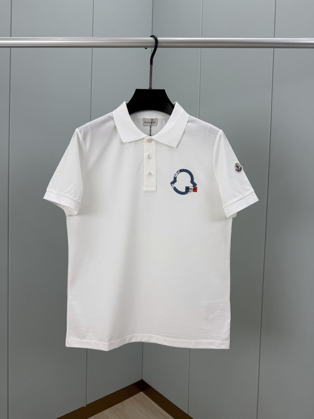 NO:839469,Moncler. SS26 Summer Printed Logo Polo Shirt, presented in the form of new season elements, with front button closure, decorated with outline printed logo and French red, white and blue flag, paying tribute to the brand's historical origins when it was founded in Monested-de-Clermont, France. The left sleeve is decorated with a classic felt wool embroidery badge. It is made of 60-count double-strand mercerized pique cotton fabric, with bright luster, good wrinkle resistance, comfortable and breathable upper body, high-quality fabric; color black, white  Size M～XXXL,,Moncler,19860909Moncler.蒙口 SS26夏季印花logo标识Polo衫,以新季元素形式呈现,正面纽扣开合,饰有轮廓印花标识和法式红白蓝三色旗帜,致敬品牌创立于法国莫内斯捷德克莱蒙的历史渊源,左袖饰有经典毡艺羊毛刺绣徽章.采用60支双股丝光珠地棉面料,光泽明亮抗皱性佳、上身舒适透气、高品质面料； 颜色黑色、白色 尺码M～XXXL,,Moncler,,Men's clothing
