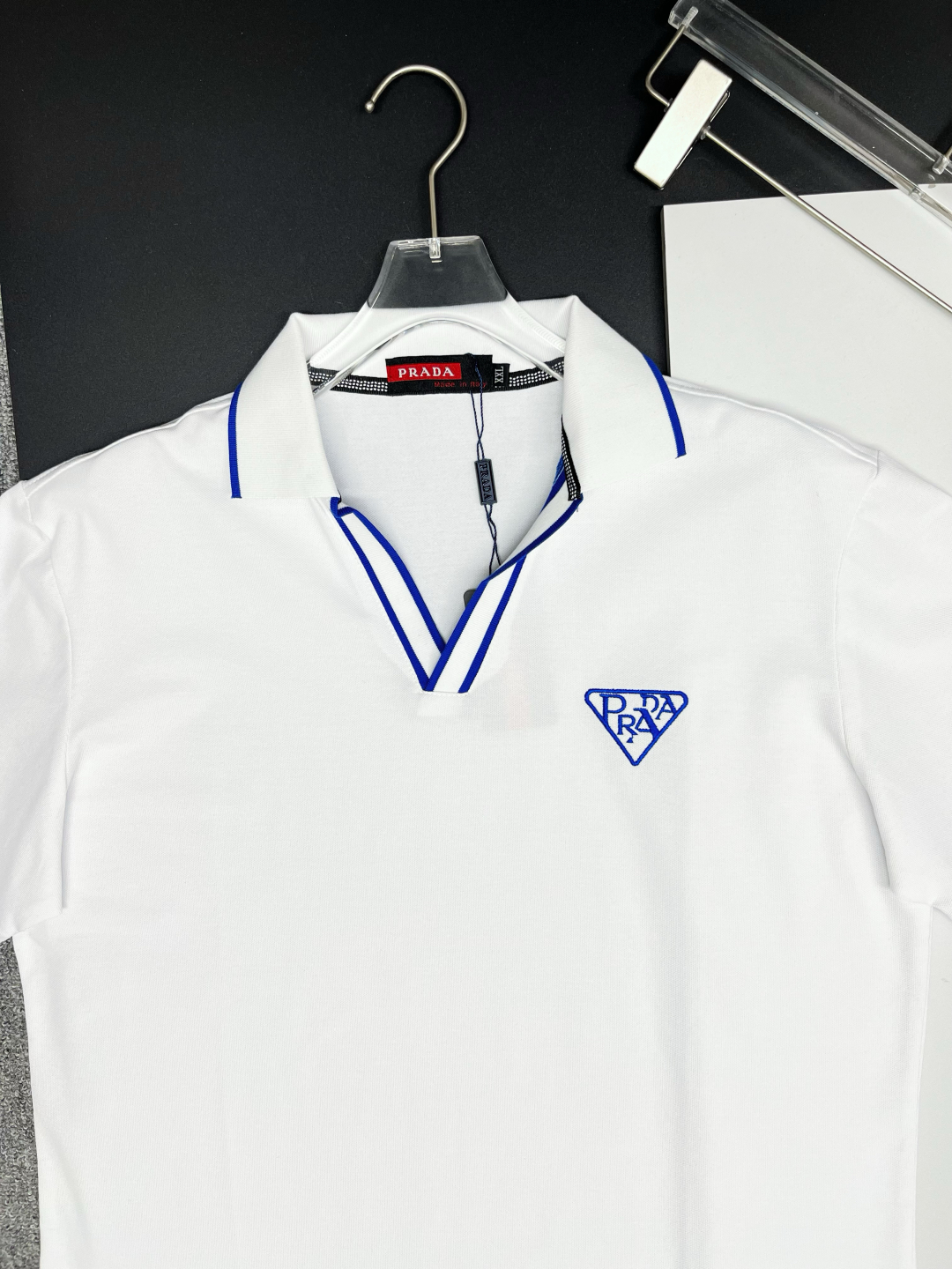 P120
  PRADA 普拉达  V领刺绣新款Polo衫
原版面料 原版订制辅料 官方同款 
采用210克丝光珠地面料，定制 同缸染面料  手感非常舒服爽滑  版型挺阔有型 
一线品牌代工厂出品 进口百灵达刺绣机器 刺绣饱满有质感
衣领袖口罗纹采用进口纱线织造 久穿不变形
春夏最新款式  时尚又个性  超级百搭好看的一款                
男女都非常合适  人手必备款 
颜色: 黑色 白色 红色
尺码：M-3XL