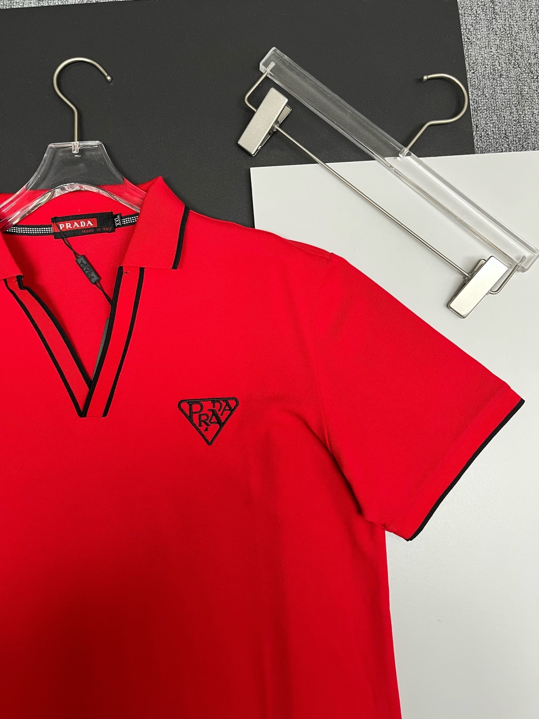 P120
  PRADA 普拉达  V领刺绣新款Polo衫
原版面料 原版订制辅料 官方同款 
采用210克丝光珠地面料，定制 同缸染面料  手感非常舒服爽滑  版型挺阔有型 
一线品牌代工厂出品 进口百灵达刺绣机器 刺绣饱满有质感
衣领袖口罗纹采用进口纱线织造 久穿不变形
春夏最新款式  时尚又个性  超级百搭好看的一款                
男女都非常合适  人手必备款 
颜色: 黑色 白色 红色
尺码：M-3XL