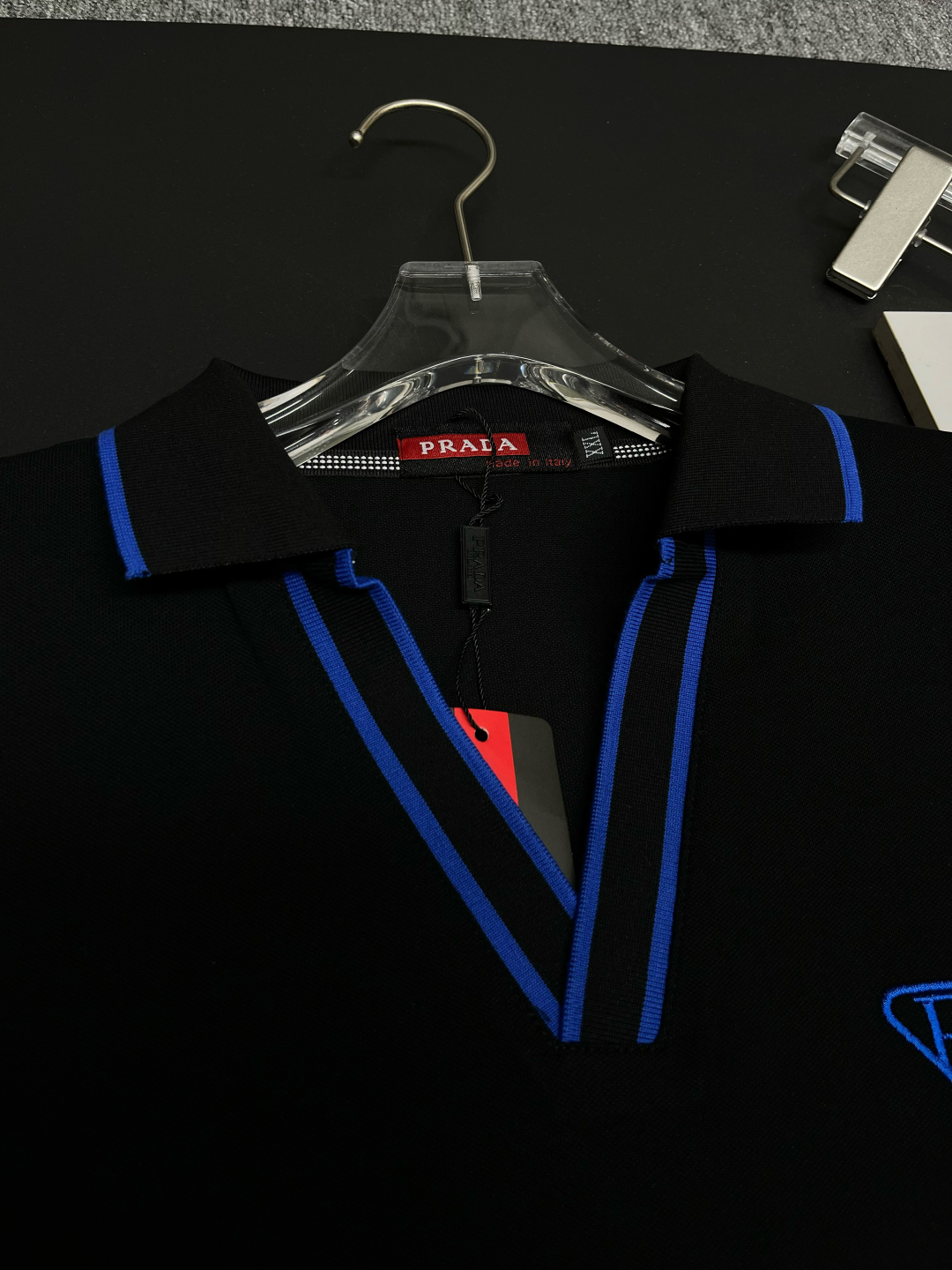 P120
  PRADA 普拉达  V领刺绣新款Polo衫
原版面料 原版订制辅料 官方同款 
采用210克丝光珠地面料，定制 同缸染面料  手感非常舒服爽滑  版型挺阔有型 
一线品牌代工厂出品 进口百灵达刺绣机器 刺绣饱满有质感
衣领袖口罗纹采用进口纱线织造 久穿不变形
春夏最新款式  时尚又个性  超级百搭好看的一款                
男女都非常合适  人手必备款 
颜色: 黑色 白色 红色
尺码：M-3XL