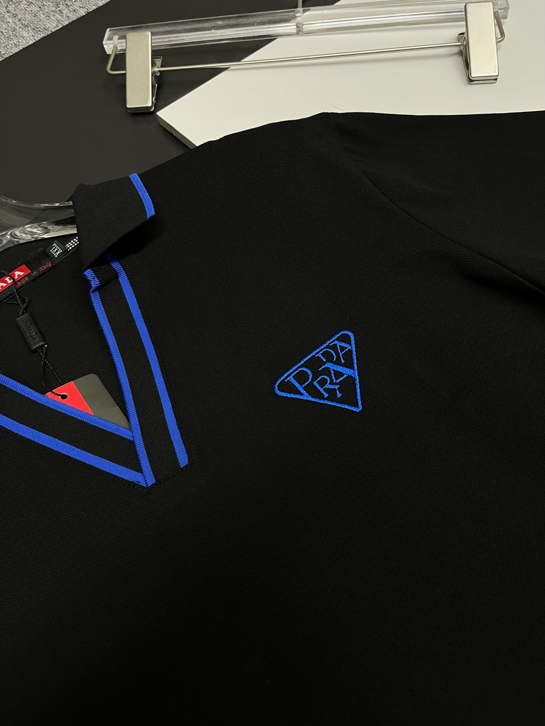 P120
  PRADA 普拉达  V领刺绣新款Polo衫
原版面料 原版订制辅料 官方同款 
采用210克丝光珠地面料，定制 同缸染面料  手感非常舒服爽滑  版型挺阔有型 
一线品牌代工厂出品 进口百灵达刺绣机器 刺绣饱满有质感
衣领袖口罗纹采用进口纱线织造 久穿不变形
春夏最新款式  时尚又个性  超级百搭好看的一款                
男女都非常合适  人手必备款 
颜色: 黑色 白色 红色
尺码：M-3XL
