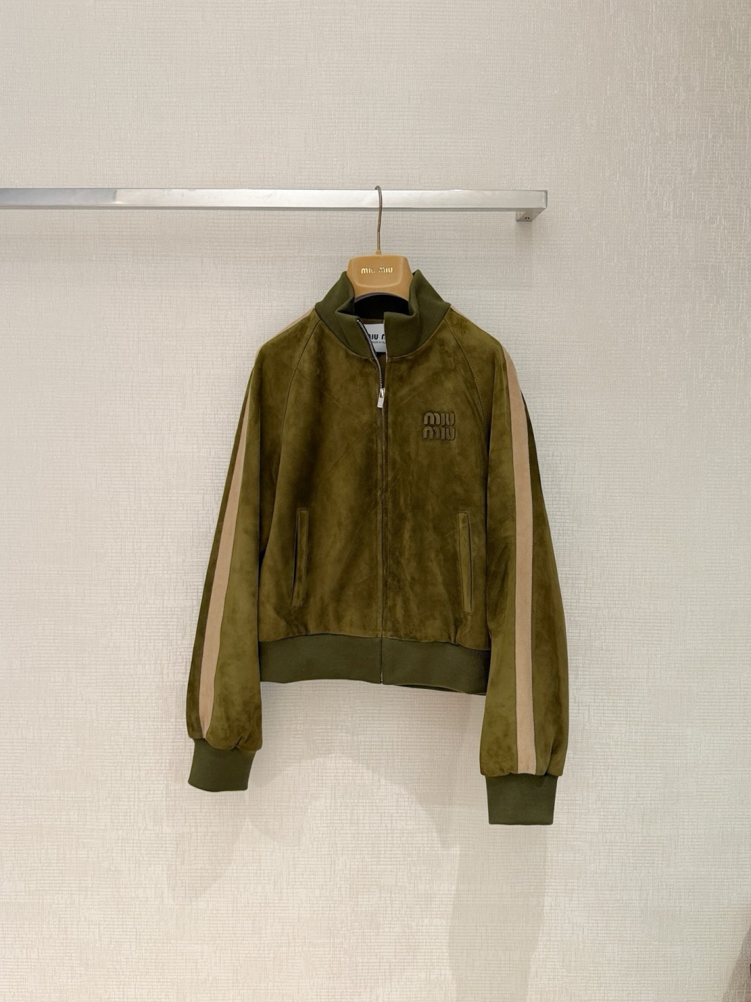NO:927394,MiuMi*26  The new spring and summer suede leather interprets modern modern style with retro sports style. It is made of genuine leather (suede) and is soft and delicate to the touch. The matte texture reveals low-key high-end luxury. The whole body is presented in classic dark brown and olive green two-color. The classic baseball collar type is matched with eye-catching off-white stripes on both sides of the sleeves to break the dullness and inject youthful vitality. The front zipper design is neat and handsome, and the chest is decorated with three-dimensional Miu of the same color.  The Miu letter logo highlights the brand recognition and exquisite workmanship in every detail. The short and loose version can not only effectively heighten the waistline and optimize the body proportions, but also has excellent tolerance. Whether it is worn with basic items, sweaters, or sweaters, it can easily create a French atmosphere that is lazy and casual yet fashionable. It is an excellent item to highlight your personality and taste in your early autumn wardrobe. Size S M L XL, Miu Miu-Clothing, miumiu, chamois leather,19860909MiuMi*26 春夏新款麂皮绒面革,以复古运动风诠释现代摩登格调.甄选真皮（麂皮）精制而成,触感绵软细腻,哑光质感中透着低调的高级奢华.整体采用经典的深棕色与橄榄绿双色呈现,经典的棒球服领型搭配袖子两侧醒目的米白色条纹拼接,打破沉闷,注入青春活力.正面拉链设计利落帅气,胸前点缀同色系立体Miu Miu字母徽标,于细节处彰显品牌辨识度与精致做工.短款宽松的版型不仅能够有效拉高腰线、优化身材比例,更兼具极佳的包容性,无论是内搭基础款、针织衫,还是,都能轻松营造出一种慵懒随性又不失时髦度的法式氛围感,是您早秋衣橱中彰显个性与品味的绝佳单品. 码数S M L XL,缪缪-服装,miumiu,chamois leather,,Women's clothing