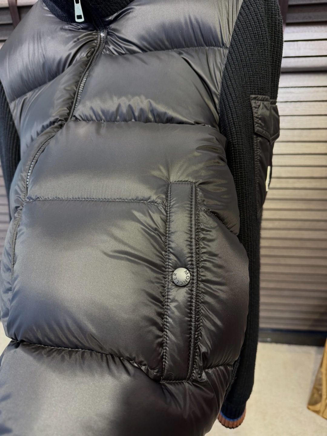 🌹 P320 羽绒 Moncl&蒙👄FW2025新款立挺针织羽绒拼接外套。柜子在售爆款。采用原版羊毛➕抗起球纤维定制混纺面料，胸前是内充90绒，后背整片高支数羊毛针织面料，立挺有型时尚，加入抗起球纤维，降低起球概率。袖子饰以品牌logo，辨识度极高；客供五金辅料，品牌工厂出品，细节之处无可挑剔；立体裁剪，上身有型；一款高品质的外套，随意穿搭都好看。
【颜色】黑色 //9107
【码数】L-4XL