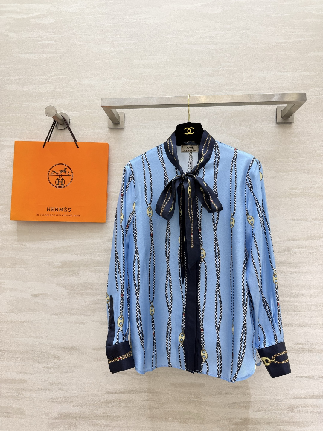 NO:933582,Hermès chain printed ribbon silk shirt has a refreshing light blue background. Classic chain vertical pattern print. Full retro noble atmosphere. Navy blue contrasting ribbon bow at the neck. Can be tied or loose. Multiple ways to wear. Navy blue cuffs with contrasting design. Exquisite details. Smooth drape silk fabric. The upper body has a soft light texture. Loose and neat fit. Suitable for commuting and daily life regardless of body shape!  High-quality customization, available in stock, size 36/38/40/42 (shoulder width 38, width 39, chest 100, length 67), Hermès-clothing, hermes, hermes, shirts, real silk,19860909Hermès链条印花飘带真丝衬衫清爽浅蓝底色 经典锁链竖纹印花 复古贵气氛围感拉满 领口藏青撞色飘带蝴蝶结 可系可散 多种穿法 藏青色袖口撞色设计 细节精致考究 顺滑垂坠真丝面料 上身自带柔光质感 宽松利落版型 不挑身形,通勤、日常都合适！高品质定制 现货首发size36/38/40/42（38肩宽39,胸围100,衣长67）,爱马仕-服装,hermes,hermes,shirts,real silk,,Women's clothing