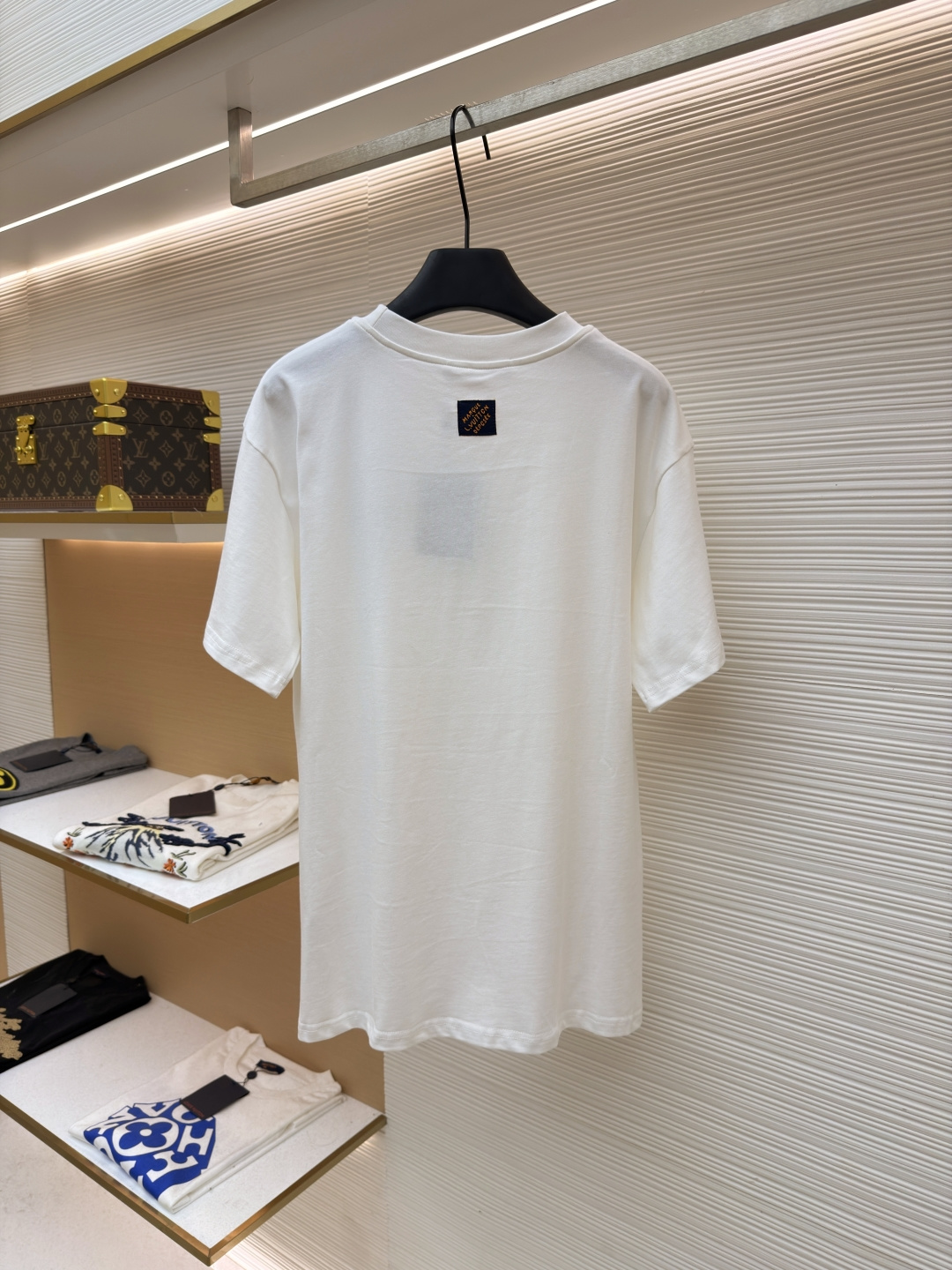 P125 LOUIS VUITTON 皮标标识短袖
●货号：1682622-A00
●面料：全棉面料
●工艺：手工缝标制作
●颜色：白色
●版型：合身版型
●克重：约255克
●尺码：S-M-L-XL
●描述：这款LV白色短袖T恤采用高支双股精梳棉面料，经预缩水处理，触感柔软亲肤且久洗不易变形，圆领采用双层罗纹针织工艺，弹力适中贴合颈部，边缘经加固锁边处理防止松弛卷边。左胸的品牌标识牌选用头层牛皮材质，表面压印品牌标识，通过高温热压工艺与衣身牢固贴合，兼具辨识度与高级质感。衣身采用平缝工艺拼接，缝线细密平整，袖口与下摆采用同料包边处理，避免磨损脱线，整体版型为宽松落肩设计，兼顾舒适体感与简约调性，所有细节均遵循品牌严苛工艺标准，是兼具实穿性与品牌辨识度的日常单品。整体走线平直细腻，面料舒适柔软，颜色一致无色差 能与同款搭配营造时尚造型，驾驭各种场合，定制辅料，三标齐全，男女同款！