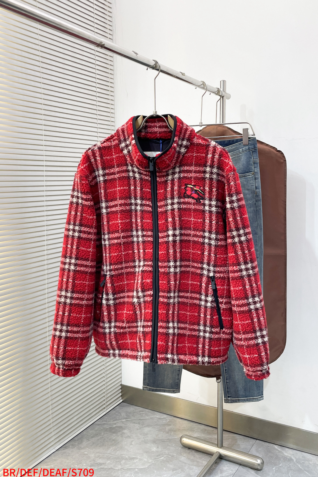 NO:732818,S709 BR Burberry plaid wool blend suede fabric selection  Selected wool and polyester fiber are scientifically blended, customized with true red as the base, intertwined with cream white and dark brown plaid lines to form a classic Scottish plaid pattern with great visual impact, constructing a fabric system that is both soft and durable. The natural curl of wool and the delicate texture of cashmere form a three-dimensional air layer, giving the fabric excellent warmth retention properties; polyester fiber improves the wear resistance of the fabric with its high strength properties  , effectively resists pilling and snagging in daily wear, and extends the service life. After a special raising process, a dense and uniform granular pile is formed, which is as fluffy and soft as a cloud, has no itching sensation when applied to the skin, and is moist and skin-friendly. The pile structure not only enhances the air storage capacity of the fabric, improves the warmth factor, but also gives the navy blue base a delicate matte matte texture, showing a high-end texture in a low-key manner.  The lining selection is designed with lightweight mesh fabric, which not only ensures warmth, but also accelerates air circulation through the mesh structure to avoid the stuffy feeling of traditional thick fabrics and achieve a comfortable balance of 'warmth on the outside and breathable on the inside'. The whole body is pre-shrunk and combined with the dimensional stability of polyester fiber, it can still maintain the original shape after multiple washings, and the shrinkage rate is controlled within 0.5 to ensure long-term stiffness. Details  The stand-up collar is designed to fit the curve of the neck, effectively blocking the intrusion of cold wind, and the edges of the collar are wrapped with contrasting colors to enhance the sense of structure; the custom-made two-way metal zipper has precise teeth, smooth and easy to pull, and the opening and closing can be adjusted up and down. The hem has a built-in adjustable drawstring, which can be adjusted by the elastic buckle, and can be freely tightened according to needs, creating a neat or casual look; the cuffs have built-in high-elastic beef tendons, which fit tightly around the wrist to prevent the intrusion of cold wind, while ensuring flexibility during activities without a sense of restraint.  Craftsmanship Embroidery details The knight's armor and horse body muscle lines are made of polyester fiber + elastic fiber blended embroidery thread, and the terry embroidery process is used to create a raised texture to enhance the relief and tactile layering of the pattern; the streamer part is made of embroidery thread containing metal-plated fibers, which is presented through flat embroidery process. The metallic luster changes with the angle of the light, such as sunlight shining on the fabric, giving the logo a flowing sense of light and shadow. Sizes S-XL are available in three standards. Next day, burberry,19860909S709 BR 巴宝莉 格纹羊毛混纺绒面 面料选择 精选羊毛与聚酯纤维科学混纺,定制正红色为基底,交织奶油白与深咖色格纹线条,形成极具视觉冲击力的经典苏格兰格纹图案,构建兼具柔软与耐用的面料体系.羊毛的天然卷曲与羊绒的细腻肌理形成立体空气层,赋予面料卓越的保暖性能；聚酯纤维则以其高强度特性提升面料耐磨性,有效抵抗日常穿着中的起球与勾丝,延长使用寿命.通过特殊起绒工艺之后,形成密集且均匀的颗粒状绒头,触感如云朵般蓬松软糯,贴肤时无刺痒感,温润亲肤.绒头结构不仅增强了面料的空气储存量,提升保暖系数,更让藏青色基底呈现细腻的哑光雾面质感,低调中透着高级肌理. 内衬选择 采用轻盈网眼布设计,在保证保暖的同时,通过网眼结构加速空气流通,避免传统厚面料的闷热感,实现“外暖内透”的舒适平衡.整体经过预缩处理,结合聚酯纤维的尺寸稳定性,多次洗涤后仍能保持原有版型,缩水率控制在0.5以内,确保长期挺括. 细节 立领设计贴合颈部曲线,有效阻挡寒风侵入,领口边缘采用撞色包边工艺,增强结构感；定制双向金属拉链,齿牙精密咬合,顺滑易拉,上下均可调节开合度.下摆内置可调节抽绳,通过松紧扣控制调节,可根据需求自由收束,塑造利落或随性两种造型；袖口内置高弹牛筋,紧密贴合手腕,防止冷风灌入,同时保证活动时的灵活性,无束缚感. 工艺 绣花细节 骑士铠甲与马身肌肉线条采用聚酯纤维+弹性纤维的混纺绣线,通过毛巾绣工艺塑造凸起纹理,增强图案的浮雕感与触感层次；飘带部分采用含金属镀纤维的绣线,通过平绣工艺呈现,金属光泽随光线角度变幻,如阳光洒在面料上,赋予徽标流动的光影感. 尺码S-XL 三标齐全 隔天,,burberry,,Men's clothing