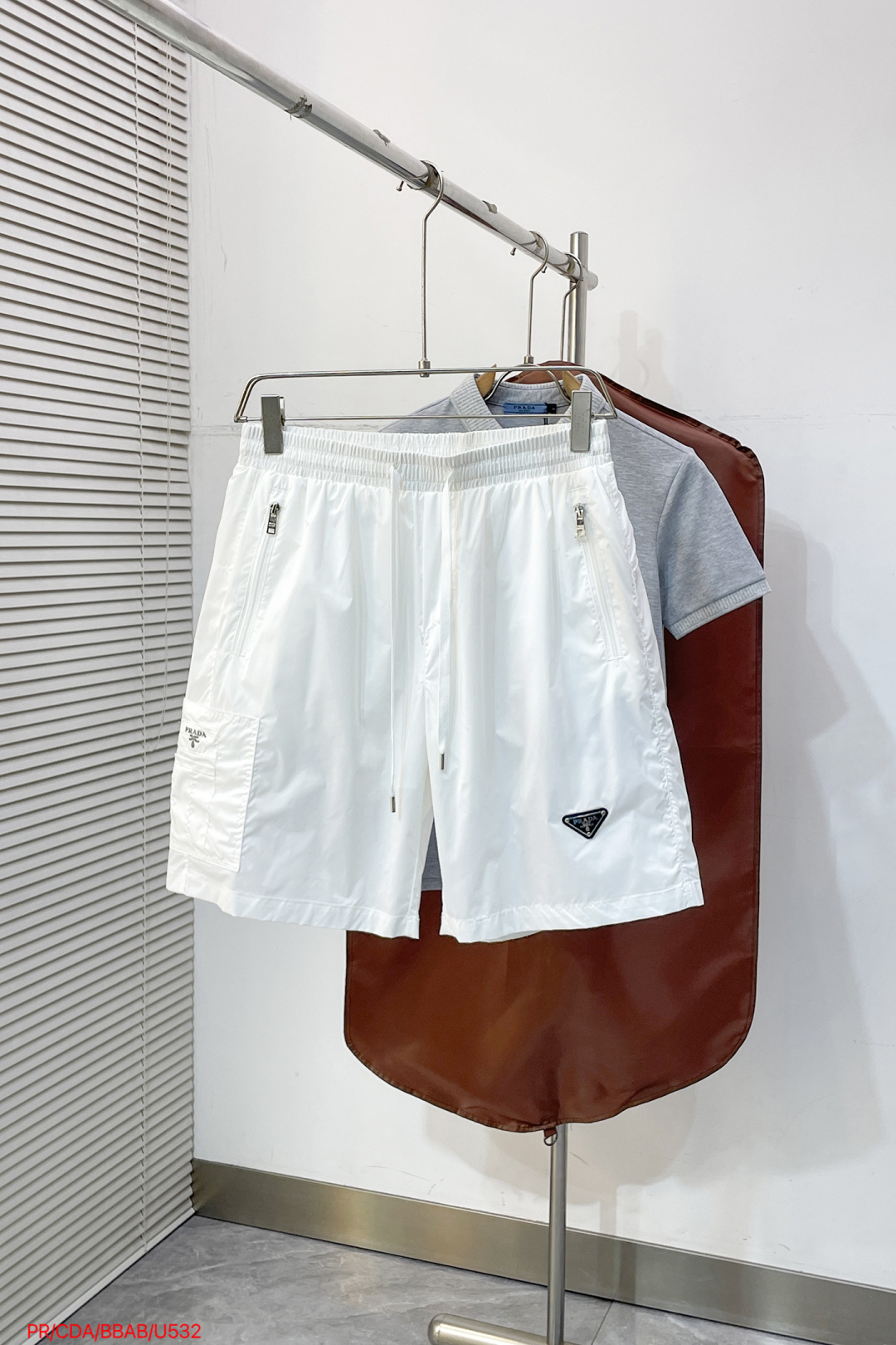 NO:838434,U532 PR Prada Prada  2026ss summer classic triangle logo functional shorts, reconstructing summer casual aesthetics with minimalist lines. High-density anti-wrinkle nylon fabric is selected, which is smooth to the touch and has excellent breathability. It is light and burdenless to wear in summer; the elastic drawstring design at the waist is suitable for various body shapes and can be matched with  Equipped with double zipper side pockets and three-dimensional work patch pockets, the storage is full of security. The iconic enamel triangle logo on the front is the finishing touch, the webbing logo on the back has rigorous details, and the neat straight silhouette modifies the leg shape. Whether you are commuting in the city or traveling outdoors, you can easily create a high-end sense of relaxation.  Color Black White Size M-3XL,,prada,prada,shorts,19860909U532 PR Prada 普拉达 2026ss夏季经典三角标机能短裤,以极简线条重构夏日休闲美学.甄选高密抗皱锦纶面料,触感顺滑且具备极佳透气性,夏日穿着轻盈无负担；腰头弹力抽绳设计适配各种身形,搭配双拉链侧袋与立体工装贴袋,收纳安全感拉满.正面标志性珐琅三角徽标点睛,背面织带标细节严谨,利落直筒版型修饰腿型,无论是都市通勤还是户外出行,皆能轻松演绎高阶松弛感. 颜色黑色 白色 码数M-3XL,,prada,prada,shorts,,Men's clothing