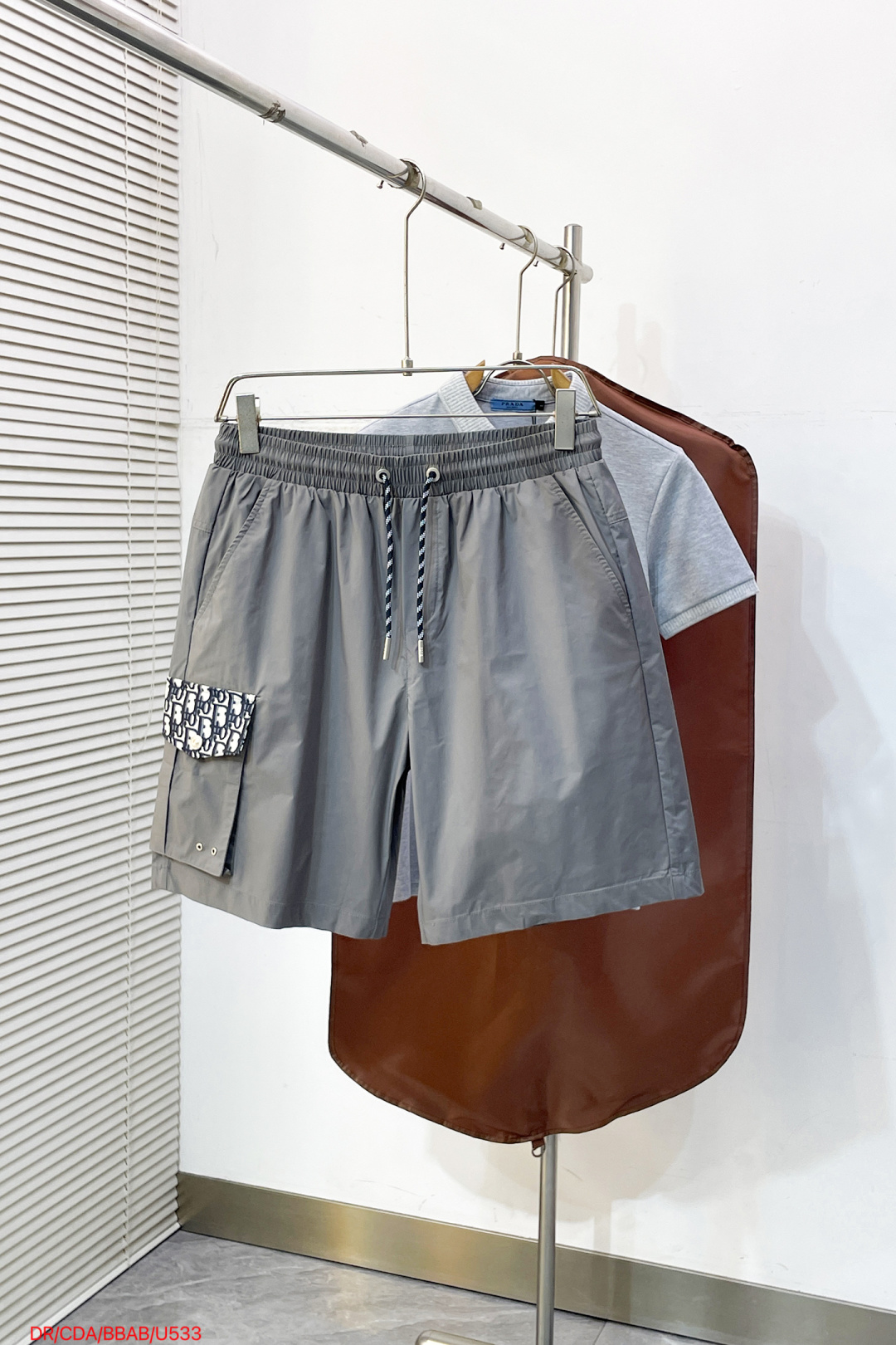 NO:838508,U533 Dior DR Dior  2026ss summer Oblique presbyopic patchwork casual shorts, available in two colors of navy and gray, combine the brand's iconic presbyopic elements with minimalist tailoring to create a high-end texture. Made of high-density anti-wrinkle nylon fabric, the upper body is light and breathable, with a smooth drape, without fear of summer heat and wrinkles; the waistband is made of contrasting woven drawstrings  Designed with both comfort and exquisite details in mind. The Oblique patch pockets on the side are matched with metal buckles, and the DIOR logo patch pocket on the back strictly echoes it, perfectly balancing brand recognition and functionality. The neat straight silhouette modifies the leg shape. Whether you are commuting in the city or traveling on vacation, you can easily interpret a relaxed and noble summer style.  Size M-3XL,,dior,dior,shorts,19860909U533 Dior DR 迪奥 2026ss夏季Oblique老花拼接休闲短裤,藏青灰双色可选,以品牌标志性老花元素与极简剪裁碰撞出高阶质感.甄选高密抗皱尼龙面料打造,上身轻盈透气,自带顺滑垂坠感,无惧夏日闷热与褶皱；腰头采用撞色编织抽绳设计,兼顾舒适与精致细节.侧边Oblique老花贴袋搭配金属扣,背面DIOR标识贴袋严谨呼应,完美平衡品牌辨识度与机能实用性,利落直筒版型修饰腿型,无论是都市通勤还是度假出行,皆能轻松演绎松弛显贵的夏日格调. 码数M-3XL,,dior,dior,shorts,,Men's clothing