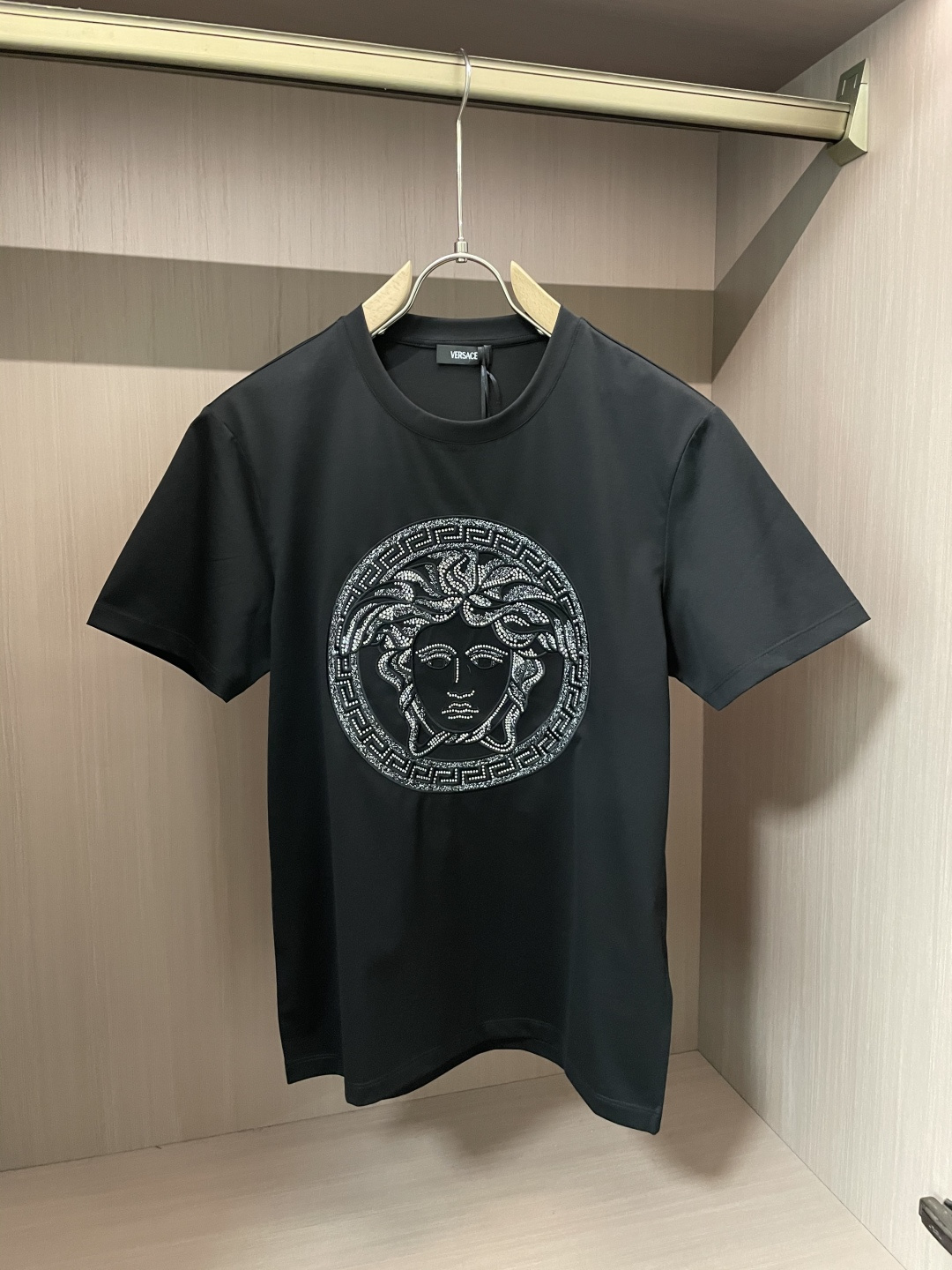 NO:125088,Versace's new spring and summer 2025 gold and silver wire hollow embroidery short-sleeved T-shirt is decorated with Medusa thread rust pattern, embellished with small crystal decoration and gold and silver wire. It has a unique and perfect design. Gold and silver wire embroidery is completely different from ordinary embroidery. It requires a very high standard German imported machine to complete it slowly. If you are not careful, it will easily break the thread, resulting in the beautiful pattern. The diverse design concepts create luxurious boutiques. Versace produces must be boutiques!  No one can say 