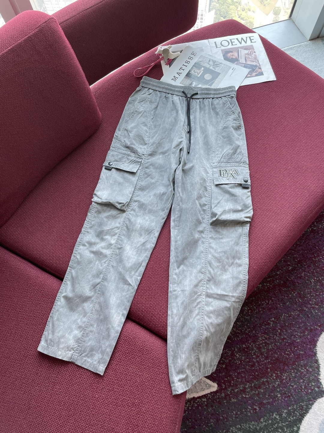 NO:132945,Prad light gray workwear style trousers are a model of both fashion and practicality. The soft light gray tone is simple but not without style, exuding a casual and free atmosphere, and it is easy to adapt to various styles. The waist drawstring design allows flexible adjustment of elasticity to ensure a comfortable fit. The large pockets on both sides are paired with flip covers and buttons, which not only adds the iconic elements of the workwear style, but also provides sufficient storage space to facilitate the placement of personal belongings. The exquisite letter embroidery on the right pocket shows the unique personality and detail texture. The fabric is comfortable and has a certain degree of clarity and wear resistance. The straight-pin style modifies the leg lines and the neat trouser leg design. Whether it is paired with sports shoes to create a casual and sporty style or a combination with shoe to create a street fashion, it can be easily controlled, helping you show an eclectic fashion attitude and show your unique charm in daily travel.  Size M-XXXL, prada,sneakers,alexander wang19860909Prad 浅灰色工装风长裤,是时尚与实用兼具的典范.柔和的浅灰色调,简约而不失格调,散发着随性自在的气息,轻松适配多种风格穿搭. 腰部抽绳设计,可灵活调节松紧,确保舒适贴合.两侧大口袋搭配翻盖与纽扣设计,不仅增添工装风格的标志性元素,还提供充足的储物空间,方便放置随身物品.右侧口袋上精致的字母刺绣,低调彰显独特个性与细节质感. 面料质感舒适,兼具一定挺括度与耐磨性.直筒版型修饰腿部线条,利落的裤脚设计,无论是搭配运动鞋打造休闲运动风,还是与板鞋组合营造街头潮流感,它都能轻松驾驭,助你展现不拘一格的时尚态度,在日常出行中尽显独特魅力. 尺码M-XXXL,,prada,sneakers,alexander wang,Men's clothing