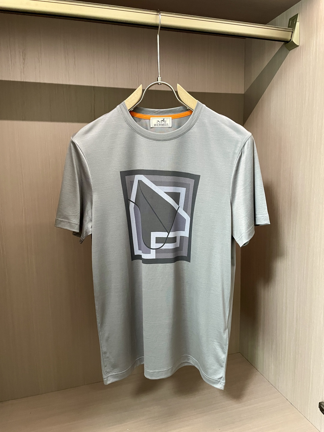 NO:443278,The overall color of Aess is soft and restrained, exuding a low-key and high-end feeling. The classic round neck design fits the neck, simple and elegant, and can show a casual and stylish temperament whether it is daily travel or casual gathering. The pattern on the front of the T-shirt is unique and composed of gray geometric figures of varying shades, with simple and smooth lines, and a sense of modern art. The pattern seems simple, but it contains Hermes' unique design aesthetics, which low-keyly demonstrates the brand identity and fashion taste.  In terms of fabric, it adheres to Hermes' consistent high-quality standards, with soft and delicate touch, skin-friendly and breathable, and is comfortable to wear. It also has good elasticity and drape, which can maintain the style of the clothes and is not easy to deform. This T-shirt combines Hermes' exquisite craftsmanship with fashion concepts, and is ideal for those who pursue quality and personality, showing luxurious charm in the subtleties. The fabric is imported from Austria, with a superb touch, and is softer and smoother to the touch than ordinary mercerized cotton, and is more refreshing and comfortable to wear. It will not fade and not deform after wearing for a long time. Size M-3XL (model 172 cm 148 catties and try on L size), hermes,tees, t-shirt, alexander wang19860909爱仕 新品 整体色调柔和而内敛,散发着一种低调的高级感.经典圆领设计,贴合颈部,简约大方,无论是日常出行还是休闲聚会,都能展现出随性又不失格调的气质. T恤正面的图案独具匠心,以深浅不一的灰色几何图形构成,线条简洁流畅,富有现代艺术感.图案看似简约,却蕴含着爱马仕独特的设计美学,低调地彰显品牌身份与时尚品味. 面料上,秉承爱马仕一贯的高品质标准,触感柔软细腻,亲肤透气,穿着舒适自在.同时具备良好的弹性与垂坠感,能保持衣物的版型,不易变形.这款T恤将爱马仕的精湛工艺与时尚理念相融合,是追求品质与个性人士的理想之选,于细微处尽显奢华韵味. 面料奥地利进口兰精天丝兰,手感超级赞,摸上去比一般丝光棉更加柔软顺滑,穿着更加冰爽舒适,且久穿久洗不褪色不变形.尺码M-3XL（模特172厘米148斤试穿L码合适）,,hermes,tees，t-shirt,alexander wang,Men's clothing