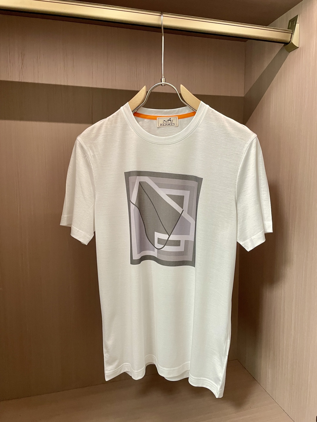 NO:495235,The overall color of Aess is soft and restrained, exuding a low-key and high-end feeling. The classic round neck design fits the neck, simple and elegant, and can show a casual and stylish temperament whether it is daily travel or casual gathering. The pattern on the front of the T-shirt is unique and composed of gray geometric figures of varying shades, with simple and smooth lines, and a sense of modern art. The pattern seems simple, but it contains Hermes' unique design aesthetics, which low-keyly demonstrates the brand identity and fashion taste.  In terms of fabric, it adheres to Hermes' consistent high-quality standards, with soft and delicate touch, skin-friendly and breathable, and is comfortable to wear. It also has good elasticity and drape, which can maintain the style of the clothes and is not easy to deform. This T-shirt combines Hermes' exquisite craftsmanship with fashion concepts, and is ideal for those who pursue quality and personality, showing luxurious charm in the subtleties. The fabric is imported from Austria, with a superb touch, and is softer and smoother to the touch than ordinary mercerized cotton, and is more refreshing and comfortable to wear. It will not fade and not deform after wearing for a long time. Size M-3XL (model 172 cm 148 catties and try on L size), hermes,tees, t-shirt, alexander wang19860909爱仕 新品 整体色调柔和而内敛,散发着一种低调的高级感.经典圆领设计,贴合颈部,简约大方,无论是日常出行还是休闲聚会,都能展现出随性又不失格调的气质. T恤正面的图案独具匠心,以深浅不一的灰色几何图形构成,线条简洁流畅,富有现代艺术感.图案看似简约,却蕴含着爱马仕独特的设计美学,低调地彰显品牌身份与时尚品味. 面料上,秉承爱马仕一贯的高品质标准,触感柔软细腻,亲肤透气,穿着舒适自在.同时具备良好的弹性与垂坠感,能保持衣物的版型,不易变形.这款T恤将爱马仕的精湛工艺与时尚理念相融合,是追求品质与个性人士的理想之选,于细微处尽显奢华韵味. 面料奥地利进口兰精天丝兰,手感超级赞,摸上去比一般丝光棉更加柔软顺滑,穿着更加冰爽舒适,且久穿久洗不褪色不变形.尺码M-3XL（模特172厘米148斤试穿L码合适）,,hermes,tees，t-shirt,alexander wang,Men's clothing