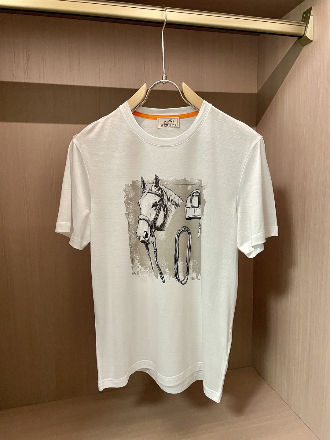 NO:443301,Aess' new product creates a simple and elegant atmosphere with pure and soft tones. The classic round neck design fits the neck lines and shows a neat and generous temperament, which can be easily controlled whether it is daily travel or casual gatherings. The pattern on the front of the T-shirt is its unique charm. It depicts the head of a horse with delicate brushstrokes, and matches the elements of horse harness to vividly show the deep connection between Hermes and horse culture. The unique artistic style of the pattern and the background treatment of the old effect adds retro charm and artistic texture, highlighting Hermes' unique design aesthetics.  In terms of fabric, it continues Hermes' consistent high-quality standards, with soft and skin-friendly texture, excellent breathability, comfortable and comfortable to wear, and has a good drape, ensuring the crisp and beautiful style. This T-shirt perfectly combines Hermes' classic elements with fashionable design, and is an ideal choice for those who pursue quality and personality, showing a luxurious style in the details. The fabric is imported from Austria, with a super touch, and is softer and smoother to the touch than ordinary mercerized cotton, and is more refreshing and comfortable to wear, and it will not fade and not deform after wearing for a long time. Size M-3XL (model 172 cm 148 catties and try on L size), hermes,tees, t-shirt, alexander wang19860909爱仕 新品 以纯净柔和的色调,营造出简约而高雅的氛围.经典圆领设计,贴合颈部线条,展现出利落大方的气质,无论是日常出行还是休闲聚会,都能轻松驾驭. T恤正面的图案是其独特魅力所在,以细腻的笔触描绘出骏马的头部,搭配马具元素,生动展现爱马仕与马文化的深厚渊源.图案的艺术风格独特,做旧效果的背景处理,增添了复古韵味与艺术质感,彰显出爱马仕别具一格的设计美学. 面料上,延续爱马仕一贯的高品质标准,质地柔软亲肤,透气性极佳,穿着舒适自在,同时具备良好的垂坠感,保证了版型的挺括与美观.这款T恤将爱马仕的经典元素与时尚设计完美融合,是追求品质与个性人士的理想之选,于细节处尽显奢华格调. 面料奥地利进口兰精天丝兰,手感超级赞,摸上去比一般丝光棉更加柔软顺滑,穿着更加冰爽舒适,且久穿久洗不褪色不变形.尺码M-3XL（模特172厘米148斤试穿L码合适）,,hermes,tees，t-shirt,alexander wang,Men's clothing