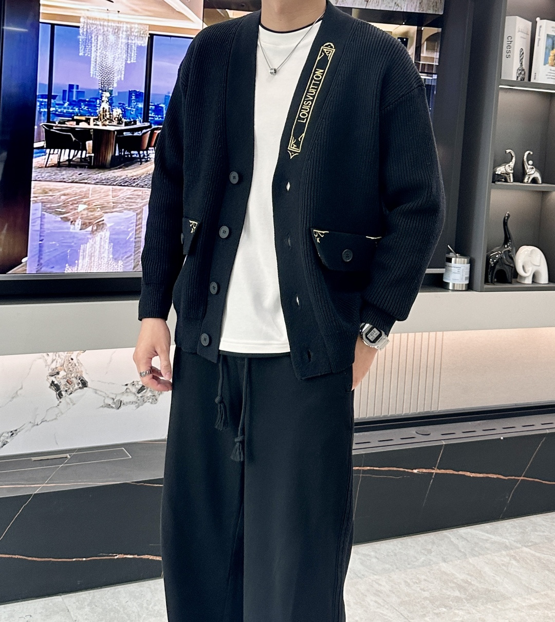 NO:540308,【Louis Vuitton Autumn and Winter Series】Classic reshaping, the minimalist and luxurious aesthetic of black knitted cardigans Design highlights When classics meet the pioneer This season's black knitted cardigans are based on the brand's iconic V-neck silhouette, integrating the 'retro futuristic' design language in autumn and winter. The golden embroidery webbing at the neckline is inspired by Louis Vuitton's classic suitcase straps, and is paired with star logo embroidery on the pocket, injecting the brand's century-old travel spirit into a modern wardrobe. Crafts details Use double-strand combed wool blend fabric, 48 high-subscription knitting technology brings a cloud-like soft touch. The 3D three-dimensional embroidery of the neckline and pocket uses imported gold wire from Italy, with 1 needle per centimeter precision thread. The front closure is customized matte black butterfly button, which is in line with Louis Vuitton's traditional suitcase lock design. The styling philosophy is minimalist and luxurious.  This cardigan redefines the luxurious and casual style with the highest 'subtraction aesthetics' and the single-breasted design creates neat lines, the length of the 65cm gold suits to a diverse body. The rotator sleeves combined with the ribbed hem create a lazy outline without losing the sense of strength. Size M-XXXL The black main tone forms a strong visual contrast with the golden logo, which easily achieves the 'low-key and rich' outfit scheming, louis vuitton, gold, alexander wang19860909【路易威登 秋冬系列】经典重塑,黑色针织开衫的极简奢华美学 设计亮点当经典遇见先锋 本季黑色针织开衫以品牌标志性的V字领廓形为基底,融合年秋冬「复古未来主义」设计语言.领口处的金色刺绣织带以路易威登经典旅行箱绑带为灵感,搭配口袋上的星形标识刺绣,将品牌百年旅行精神注入现代衣橱. 工艺细节 采用双股精梳羊毛混纺面料,48支高支数针织工艺带来云朵般柔软触感 领口与口袋的3D立体刺绣使用意大利进口金丝线,每厘米含1针精密走线 前襟定制哑光黑蝶形纽扣,暗合路易威登传统旅行箱锁扣设计  造型哲学极简即极奢 这款开衫以**「减法美学」**重新定义奢华休闲风 单排扣设计营造利落线条,65cm黄金衣长适配多元身形 落肩袖型结合罗纹收束下摆,打造慵懒而不失力量感的轮廓 尺码M-XXXL  黑色主调与金色标识形成强烈视觉对比,轻松实现「低调炫富」的穿搭心机,,louis vuitton,gold,alexander wang,Men's clothing