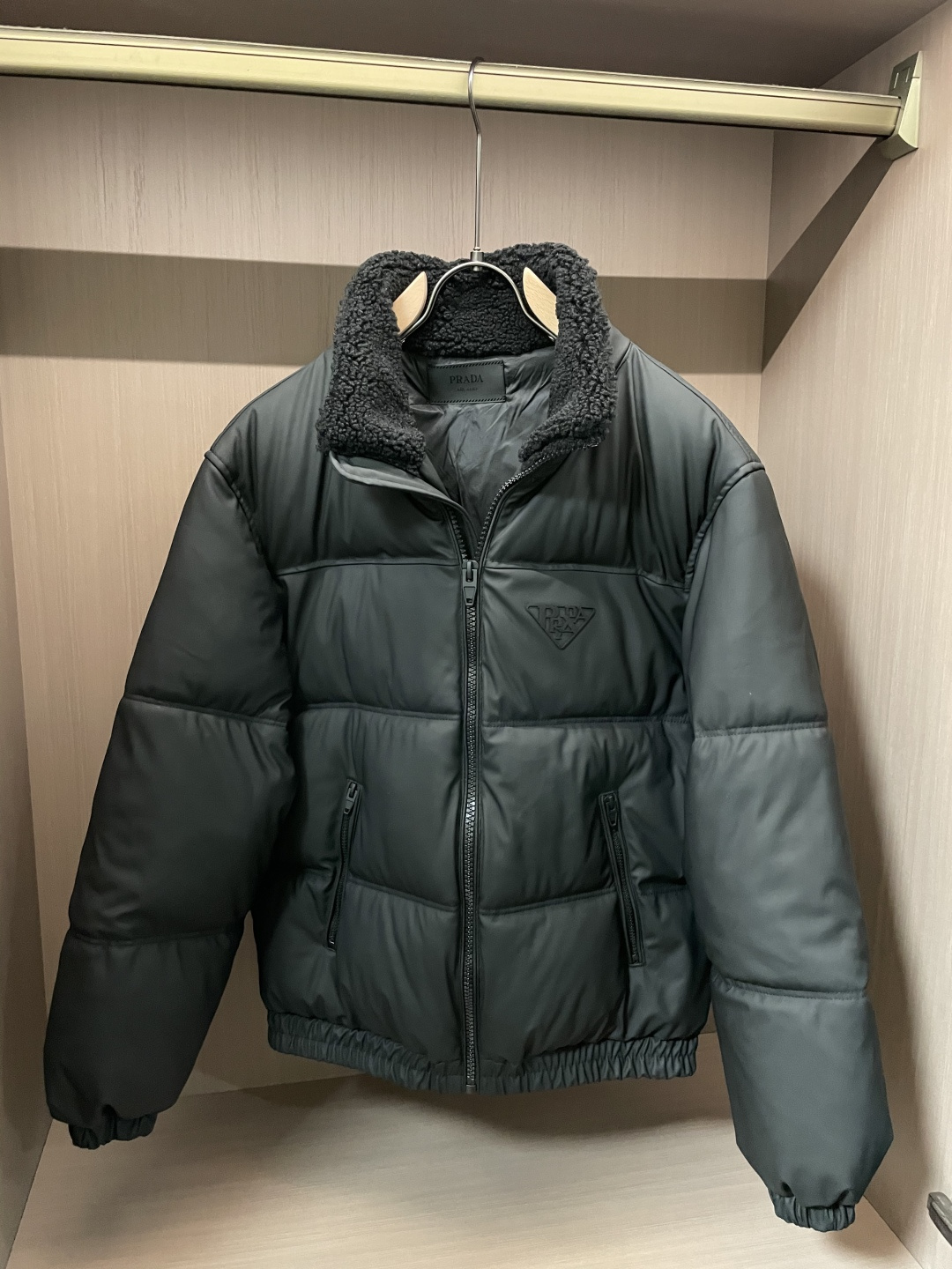 Prada都市轻奢款羊羔毛领羽绒棉棉衣 复古松弛冬日款作为Prada日常线核心款，这件棉衣以“轻奢质感+