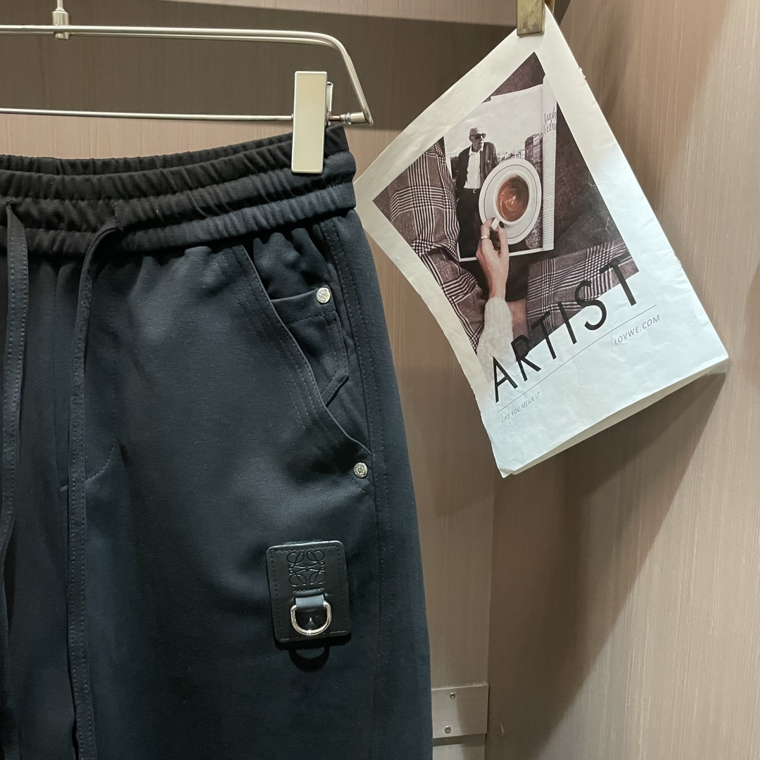 Loewe这条休闲裤，是把“轻奢巧思藏在工装细节里”的款——不是软塌的普通休闲裤，面料带细腻哑光肌理，软