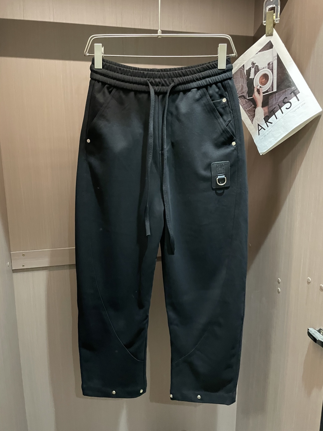 Loewe这条休闲裤，是把“轻奢巧思藏在工装细节里”的款——不是软塌的普通休闲裤，面料带细腻哑光肌理，软