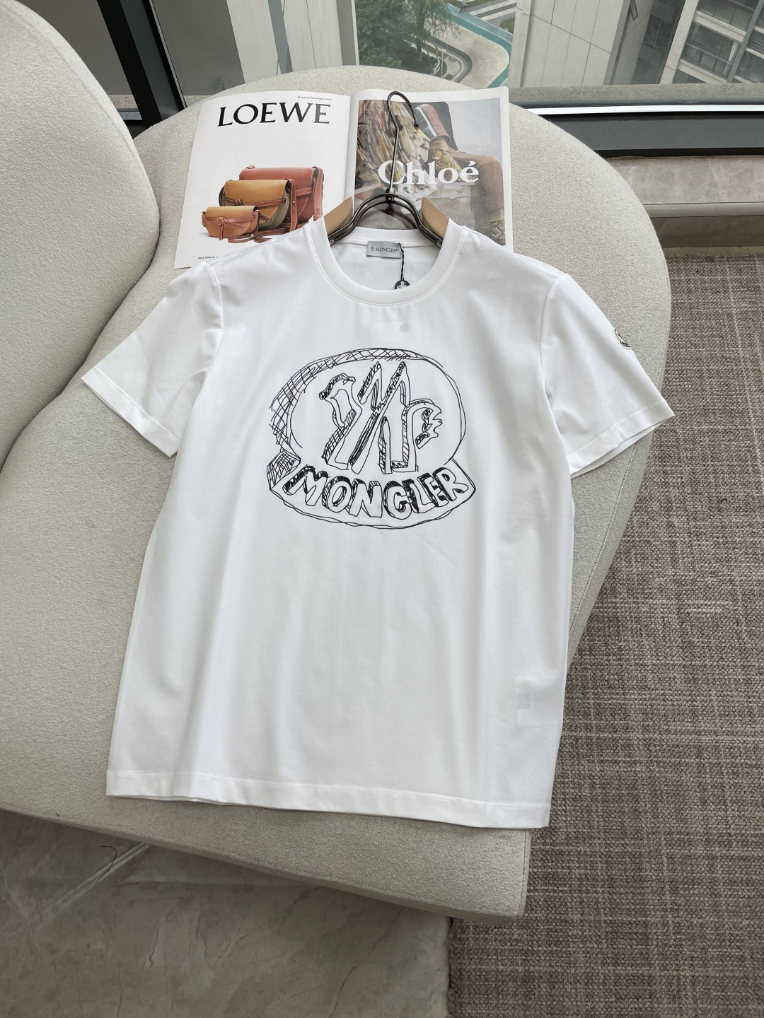 NO:841037,Moncler's 2026 new spring and summer abstract printed round neck short-sleeved T-shirt focuses on the combination of simple fashion and brand recognition. The front uses a combination of white hand-painted letters 'MONCLER' and the brand's classic 'M' logo, presenting a slightly retro and artistic fuzzy printing effect.  Visually, it retains the brand recognition without losing its trendy personality. The basic round neck design, with loose tailoring, is comfortable to wear and not flattering on the figure, suitable for daily casual and street wear. There is the brand's classic circular badge on the left cuff, and the word 'MONCLER' is clearly printed on the inner collar label, highlighting the authentic details.  Size s-xxxl,,T-shirt,tees,t-shirt,19860909Moncler2026春夏新品抽象印花圆领短袖T恤,主打简约时髦与品牌辨识度的结合.正面采用白色手绘风格的“MONCLER”字母与品牌经典“M”标志组合,呈现一种略带复古、艺术感的模糊印花效果,视觉上既保留了品牌辨识度,又不失潮流个性.基础圆领设计,搭配宽松剪裁,穿着舒适不挑身材,适合日常休闲、街头穿搭.左袖口处有品牌经典圆形徽章,内领标签清晰印有“MONCLER”字样,彰显正品细节. 尺码s-xxxl,,T-shirt,tees，t-shirt,,Men's clothing
