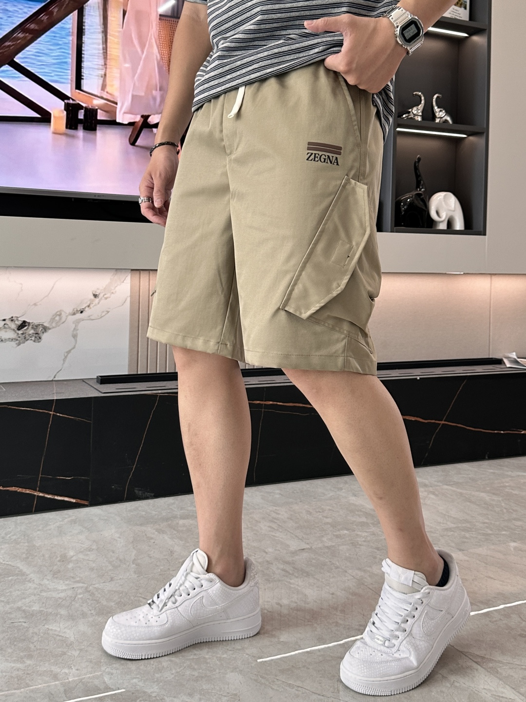 NO:858800,ZEGNA Italian-style light workwear casual shorts are made of high-grade breathable and quick-drying fabrics, which feel as smooth as silk and have an icy drape. They are thin but not transparent, do not stick to the body when sweating, and have no wrinkles when sitting for long periods of time. They can always stay neat and decent in summer. The elastic drawstring waist design says goodbye to tight constraints and adapts to various body shapes. The large side work pockets combine practicality and design, and are casual and aura.  The iconic embroidered logo is embellished, low-key and unobtrusive, and the details show the brand's texture. The khaki brown tone comes with a retro filter, which is more textured than ordinary shorts. Pair it with a white T, a linen shirt or a POLO shirt to easily achieve the 'lazy old money style'. Whether it is a coffee shop, a weekend outing or daily commuting, you can wear it with an effortless sense of sophistication. Sizes 28-36,, shorts, shirts,19860909ZEGNA 意式轻工装休闲短裤 甄选高定级透气速干面料,触感如丝绸般顺滑,自带冰感垂坠. 薄而不透,出汗不粘身,久坐无褶皱,夏日也能时刻保持利落体面.  松紧抽绳腰头设计,告别紧绷束缚,适配各种身形 侧边工装大口袋,兼顾实用性与设计感,随性中自带气场 标志性刺绣logo点缀,低调不张扬,细节尽显品牌质感 卡其棕色调自带复古滤镜,比普通短裤更显质感. 搭配白T、亚麻衬衫或POLO衫,轻松拿捏「慵懒老钱风」,无论是咖啡探店、周末出游还是日常通勤,都能穿出毫不费力的精致感 尺码28-36,,shorts,shirts,,Men's clothing