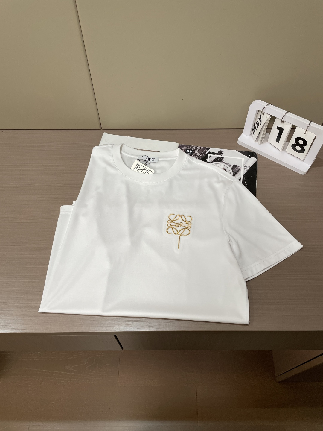 以LOEWE标志性的Anagram为灵感，这件T恤将品牌经典图腾幻化为一枚精致的金色气球刺绣，在极简的底