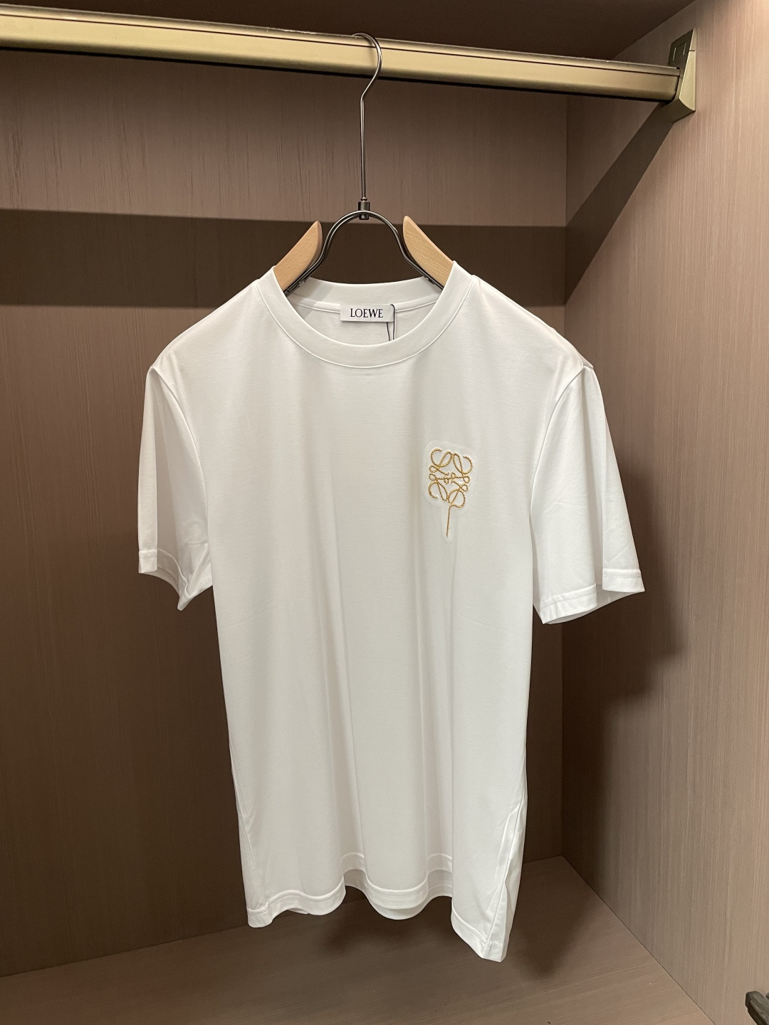 以LOEWE标志性的Anagram为灵感，这件T恤将品牌经典图腾幻化为一枚精致的金色气球刺绣，在极简的底