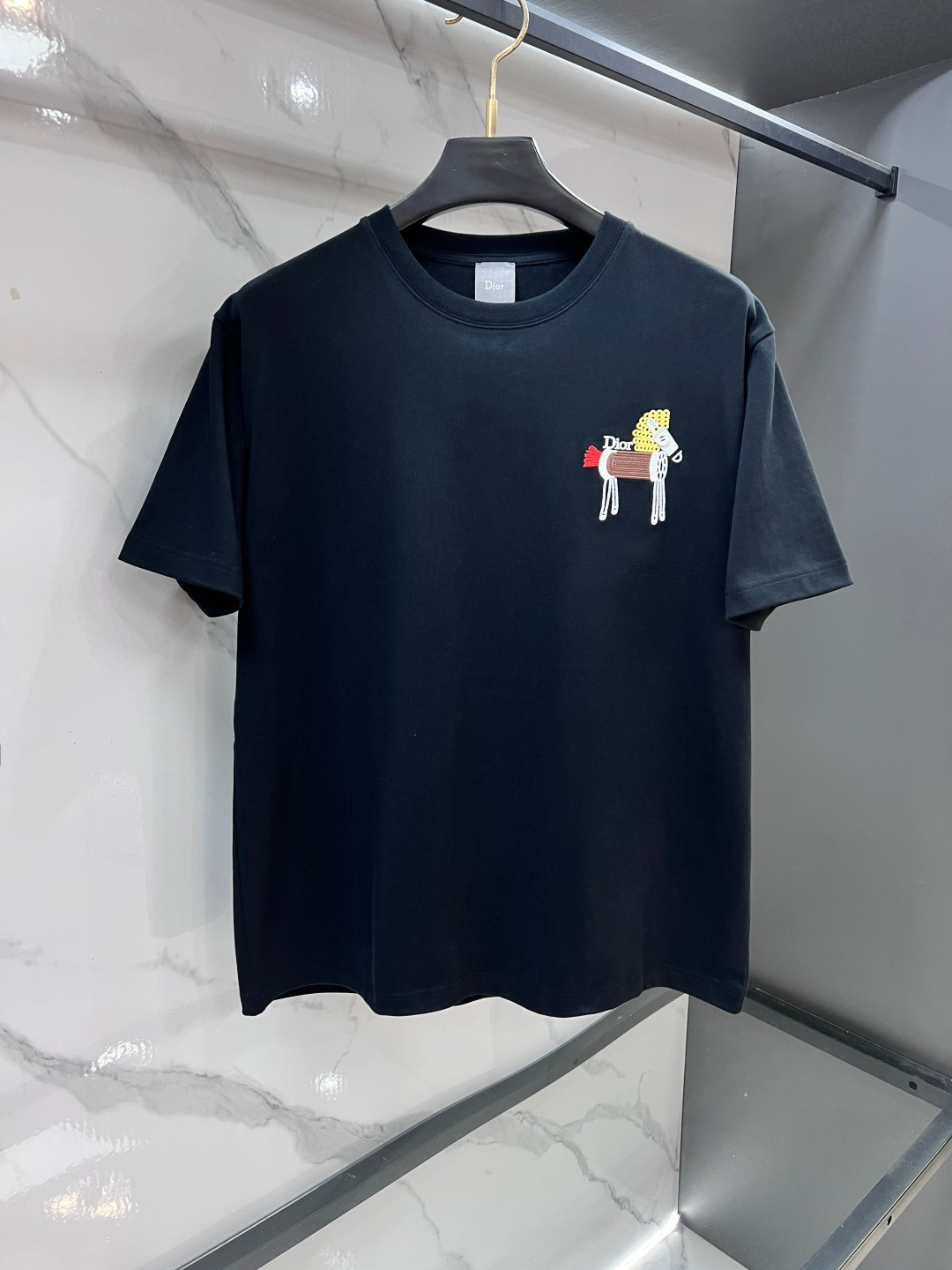 NO:912575,Dior 2026FW Year of the Horse limited special edition. This T-shirt is a new product of the 2026 spring men's wear series. It is embellished with a cartoon pony logo and buttons!  Pay tribute to the exquisite craftsmanship of the Dior atelier. Carefully crafted from cotton jersey fabric, round neck design. Classic silhouette, can be paired with jeans for a casual look.……………………………………………………………… SizeS-XL,,dior,dior,jeans,19860909迪奥 2026FW马年限定特别版 这款 T 恤是二零二六春季男装系列新品,刺饰以 卡通小马标志配以钮扣点缀其中！向 Dior 工坊的精湛工艺致敬.采用棉质平纹针织面料精心制作,圆领设计.经典廓形,可与牛仔裤搭配,打造休闲的造型.…………………………………………………… SizeS-XL,,dior,dior,jeans,,Men's clothing