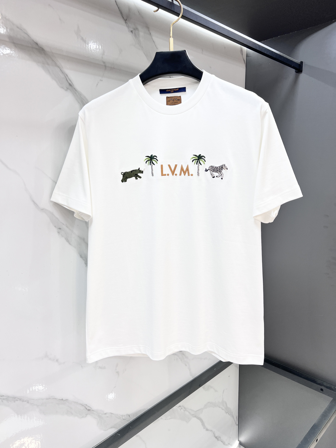 NO:915363,LV 26SS new classic cotton short-sleeved round neck T-shirt, embroidered with the 2026 spring and summer show series logo. The three-dimensional L.V.M. letter design on the chest is inspired by the brand’s traditional suitcases, surrounded by exquisite palm trees and animal patterns in the LV x The Darjeeling Limited theme pattern.…………………………………………………… SizeS-Xl,, louis vuitton, T-shirt, tees, t-shirt,19860909Lv 26SS新款经典的棉质短袖圆领T恤,绣有 2026 年春夏秀场系列标识.胸前立体感 L.V.M. 字母设计灵感源自品牌传统旅行箱,周围环绕 LV x The Darjeeling Limited 主题图案中精致的棕榈树与动物纹样.…………………………………………………… SizeS-Xl,,louis vuitton,T-shirt,tees，t-shirt,,Men's clothing