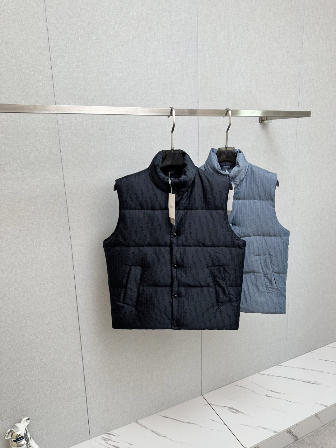 NO:573934,High version (with logo on the lining) with exclusive dust bag DR DIoR 25FW new down vest  The fabric uses scientific jacquard technology to apply laser jacquard technology to the fabric, making the entire piece more concave and convex, with a stronger three-dimensional effect. This technology not only improves the visual effect of the fabric, but also enhances the durability and comfort of the fabric. The custom-woven high-density satin nylon material, combined with the dark jacquard weave method, makes the down highly waterproof, anti-fouling, and dust-proof. This ensures that it can maintain good appearance and performance in bad weather.  Printing process Oblique printing is applied to the fabric through precise printing technology, perfectly integrating with the fabric, showing a low-key and luxurious visual effect. The down filling is strictly processed and screened to ensure the fluffiness and warmth of the down. The down is evenly filled into the liner and fixed by sewing and gluing.   Detail processing is carried out on the collar, cuffs, hem and other parts to improve the practicality and beauty. At the same time, ironing and inspection are carried out to ensure that the product quality meets the standards. Black, same style for men and women!  SIZE: S-XL three standard complete, dior, down jacket, alexander wang19860909高版本（里布有logo）配专属防尘袋 DR DIoR 25FW新款羽绒马甲 面料采用科技提花技术在面料上应用激光提花技术,使整件凹凸有致,立体感更强.这种技术不仅提升了面料的视觉效果,还增强了面料的耐用性和舒适度.定织高密度缎面尼龙材质,结合暗纹提花织法,使得羽绒具有极高的防水、防污、防尘性能.这确保了在恶劣天气下也能保持良好的外观和性能. 印花工艺Oblique印花通过精密的印刷技术应用于面料上,与面料完美融合,呈现出低调而奢华的视觉效果. 羽绒填充经过严格的处理和筛选,确保羽绒的蓬松度和保暖性.将羽绒均匀地填充到的内胆中,并通过缝制压胶等方式固定. 细节处理在的领口、袖口、下摆等部位进行细节处理,以提升的实用性和美观度.wt同时,对进行整烫和检验,确保产品质量符合标准. 黑色,男女同款！ SIZE:S-XL 三标齐全,,dior,down jacket,alexander wang,Men's clothing