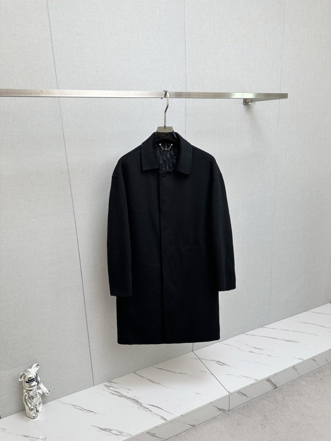 NO:615230,Dior's 2025 Autumn and Winter Men's Mid-Length Wool Coat is a contemporary interpretation of the archive genes. Retracing the essence of the brand's archives, Dior's 2025 Autumn and Winter Men's Collection launches this mid-length wool coat, which reinterprets the classic style from a modern perspective and becomes a timeless piece in the wardrobe.  Inspired by the brand's archive style, this coat is made of wool double-sided twill fabric, which is light in texture but has a crisp texture. It is refined with exquisite craftsmanship in an Italian workshop. Every detail demonstrates the ingenuity of Dior's haute couture heritage. The body is designed with a slim fit and cleverly integrated into the embedded straight sleeves and dropped shoulders. It outlines clean lines while taking into account the wearing comfort, breaking the restraint of traditional formal wear.  In the details, you can see the ingenious worsted Dior classic presbyopia lining with hidden brand imprints, forming a low-key echo with the black body; the button opening and closing of the cloth bag is simple and elegant, and the welt side pockets are both practical and beautiful. The non-slit design and unlined structure strengthen the overall neat silhouette, and the viscose fiber lining of the sleeves adds to the smooth wearing and taking off experience.  From business commuting to daily travel, this coat is based on classic black. With a design that combines retro genes and modern tailoring, it can easily adapt to multiple occasions and become an iconic item that defines contemporary men's elegance. Size M-3XL,, dior, dior, alexander wang19860909迪奥 Dior 2025秋冬男士中长款羊毛大衣典藏基因的当代演绎 回溯品牌典藏精髓,Dior 2025秋冬男士系列推出这款中长款羊毛大衣,以现代视角重释经典格调,成为衣橱中的隽永之作. 灵感源自品牌典藏款式,这件大衣选用羊毛双面斜纹面料打造,质地轻盈却兼具挺括质感,于意大利工坊经由精湛工艺精制而成,每一处细节都彰显迪奥高级订制传承的匠心底蕴.衣身采用修身版型设计,巧妙融入嵌入式直袖落肩剪裁,在勾勒利落线条的同时兼顾穿着舒适度,打破传统正装的拘谨感. 细节之处更见巧思精纺Dior经典老花内里暗藏品牌印记,与黑色衣身形成低调呼应；布包纽扣开合简约雅致,贴边侧袋兼顾实用与美观,不开衩设计与无内衬结构则强化了整体的利落轮廓,衣袖内衬粘胶纤维更添穿脱顺滑体验. 从商务通勤到日常出行,这款大衣以经典黑色为基底,凭借兼具复古基因与现代剪裁的设计,轻松适配多元场合,成为定义当代男士优雅的标志性单品 码数 M-3XL,,dior,dior,alexander wang,Men's clothing