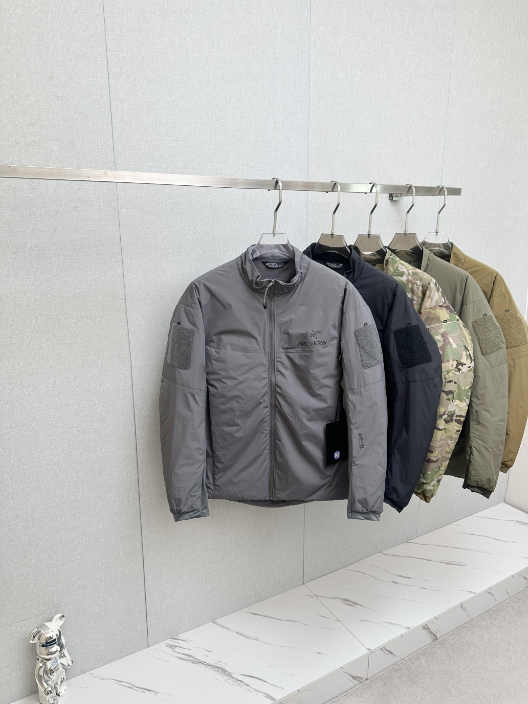 NO:655782,Arcteryx/Arc'teryx Men's and Women's Military Bird Stand Collar Cotton Jacket Leaf Cold Gen 2 Windproof and Warm Stand Collar Cotton Jacket Military Edition Wizard Grade Windproof Soft Shell Stand Collar Thick Cotton Jacket This outer layer uses N40p WINDSTOPPER 2L fabric and is filled with Coreloft 100g thermal cotton, which fills the gap in military bird medium-thickness cotton jackets. It is a hooded version of the Cold series, fully windproof, very warm, and its main features are lightness and comfort!  It is generally used as a jacket, paired with other mid-layers and underwear. The fabric is made of the famous windstopper fabric, n40p. The softness of the fabric is between the old Gossamera and Fusion WS. Therefore, it can be used for outerwear or with the middle layer of a jacket. Features 1. The outer layer of WINDSTOPPER fabric is fully windproof and has a certain ability to repel water, dew, snow, etc., with a balance of softness and durability. Filling material Coreloft  It has excellent heat-to-weight ratio and thermal insulation efficiency, and is easy to compress. It has good water repellency. 2. The vertical design of the internal waist tightening zipper has the greatest effect in preventing hooking and wear with the tactical belt. 3. The three-dimensional cut of the shoulders and elbows has excellent mobility and does not affect various tactical movements.  4. There is a zippered chest pocket on the inside, and two zippered hand pockets on the outside. There are openings inside to ensure that communication cables can pass through. There are zippered arm pockets on the left and right arms, with hanging loops inside, you can use the arm pockets to store items. Top configuration 1:1 fabric, workmanship, cotton clothing!  Low-key luxury, as warm as down!  Color Black Gray Crocodile Camouflage Ranger Green Size S-2XL SM L  coats,down jacket,hats,alexander wang19860909Arcteryx/始祖鸟男女款军鸟立领棉服 Leaf Cold Gen 2 防风保暖立领棉服 军版向导级防风软壳立领厚棉服 这款外层用了N40p WINDSTOPPER 2L面料,填充Coreloft 100克级保暖棉,填补了军鸟中等厚度棉服的空白.属于Cold 系列的有帽版本,全防风,很好的保暖,穿着轻巧舒适是其主要特点！一般作为外套使用,搭配其他中层和内衣使用.衣服面料为大名鼎鼎的windstopper面料,n40p 面料柔软度介于老款的Gossamera和Fusion的WS.所以既可用于外套,也可以搭配冲锋衣中间层使用. 特点 1外层WINDSTOPPER面料全防风,并有一定的防泼水,露,雪等能力,柔软度和耐用性均衡.填充材料Coreloft 有优秀的暖重比和热绝缘效率,易压缩性.拒水性很好. 2内部腰部收紧拉链竖直设计最大效果防止和战术腰带发生钩挂和磨损. 3肩部和手肘立体剪裁,具有优秀的运动性,不影响各种战术动作. 4内部有一个带拉链的胸袋,外部有两个带拉链的插手袋,里面有开口可保证通讯线缆通过.左右双臂都有带拉链的臂袋,里面有挂环,可以利用臂袋存放物品. 顶级配置1:1面料 做工,棉服！低调奢华,保暖性不输羽绒！ 颜色黑色 灰色 鳄鱼色 迷彩色 游骑兵绿 尺寸S-2XL SM L XL 2XL 衣长74 76 78 80 82  肩宽52 54 55 57 58 袖长 66 67 69 70 72 胸围 122 126 130 134 138,arc'teryx,jackets & coats,down jacket,hats,alexander wang,Men's clothing