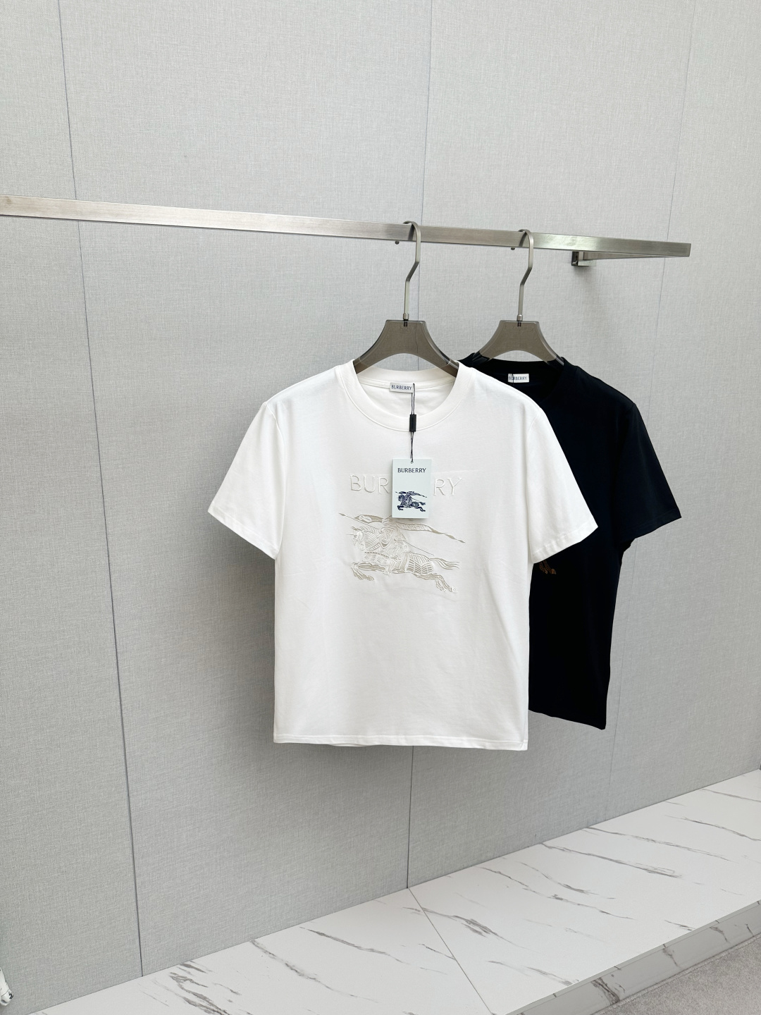 NO:655781,2026SS new product Burberr*/Burberry equestrian knight embroidered cotton knitted round neck short-sleeved T-shirt  The main body of the war horse embroidery pattern adopts precision stitch embroidery technology; the embroidery is very fine and dense, the pattern is clear and has a strong sense of line and three-dimensionality, and the embroidery body has a subtle matte visual texture; the embroidery effect is three-dimensional and full. The flat embroidery has a unique design of stitch stitching, and the embroidery is very fine and dense; the overall stitching is fine and the fineness and texture are consistent, adding a sense of layering to the simple design. Double-needle stitching to make garments  Straight cut round neck, slightly dropped shoulder line, and neat upper body. The neckline, cuffs, and hem are all made with special machine topstitching, making them more resistant to deformation after repeated wear and washing. The fabric is made of pure cotton, with high-density twill texture, fine weave of gray fabric, and no stretch to maintain the unique muscle effect. SizeS/M/L/XL/XXL,, burberry, burberry, T-shirt, tees, t-shirt, alexander wang198609092026SS新品 Burberr*/巴宝莉 马术骑士刺绣棉质针织圆领短袖T恤 战马刺绣图案主体采用精密挨针绣工艺；刺绣非常精细针法绵密,图案清晰且线条感和立体感强,绣体具有微妙的哑光视觉质感；刺绣效果立体饱满.平绣的挨针走线独特设计,刺绣非常精细针法绵密；整体针脚细密,精细度质感一致,为简约设计增添了层次感. 双针走线缝制成衣 圆领直身裁剪、合体微落肩线,上身精神利落领口、袖口、底摆均以专机车明线,多次穿洗更加不易变形.面料纯棉材质,高密度斜纹肌理,胚布织法细密,无弹力保持特有筋骨效果. SizeS/M/L/XL/XXL,,burberry,burberry,T-shirt,tees，t-shirt,alexander wang,Men's clothing