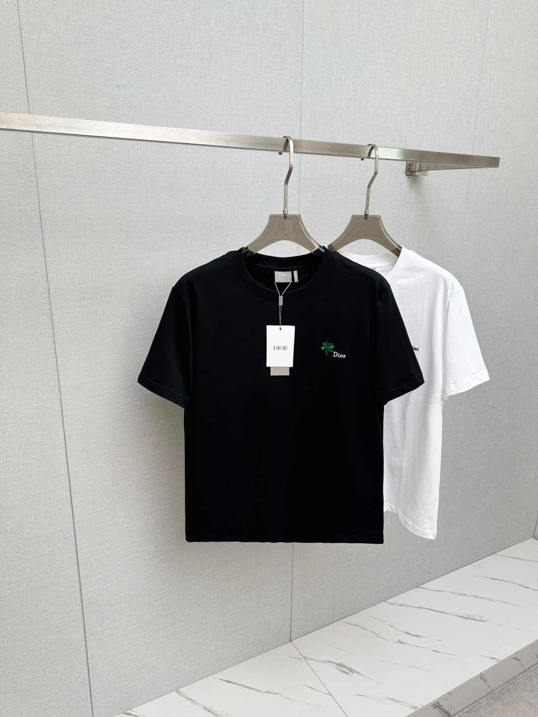 NO:841730,Dior 2026ss round neck four-leaf clover embroidered graphic T-shirt  ●Description: This black short-sleeved T-shirt is made of high-count double-ply combed cotton blend fabric. The neckline is made of high-elastic ribbing with three-needle hemming technology. It is not easy to loosen and curl after repeated wear. The side seams of the body are made of double-needle embedded clip technology, which ensures smooth and firm routing and reduces skin friction. The green clover pattern distributed on the body is made of precision.  Embroidery technology, the stitches are fine and even, the pattern is three-dimensional and full and not easy to get off-line; the ready-made garments undergo multiple quality inspection processes such as stitching, ironing, and decontamination. The version is loose and moderate, suitable for daily leisure, dating and travel and other scenarios, with both exquisite details and practical wearability. The overall wiring is straight and delicate, the fabric is comfortable and soft, and the colors are consistent without color difference.  It can be matched with the same style to create a fashionable look, and can be used in various occasions. Customized accessories, complete with three standards, same style for men and women!  Size S-2XL,,dior,T-shirt,tees,t-shirt,19860909Dior 2026ss圆领四叶草刺绣图案T恤 ●描述这款黑色短袖T恤采用高支双股精梳棉混纺面料,领口采用高弹力罗纹搭配三本针包边工艺,反复穿着不易松弛卷边；衣身侧缝采用双针埋夹工艺,走线平整牢固,减少皮肤摩擦感.衣身分布的绿色三叶草图案采用精密刺绣工艺,针脚细密均匀,图案立体饱满且不易脱线；成衣经针、整烫、去污等多道质检工序,版型宽松有度,适配日常休闲、约会出游等多种场景,兼具精致细节与实穿性.整体走线平直细腻,面料舒适柔软,颜色一致无色差 能与同款搭配营造时尚造型,驾驭各种场合,定制辅料,三标齐全,男女同款！ 尺码S-2XL,,dior,T-shirt,tees，t-shirt,,Men's clothing