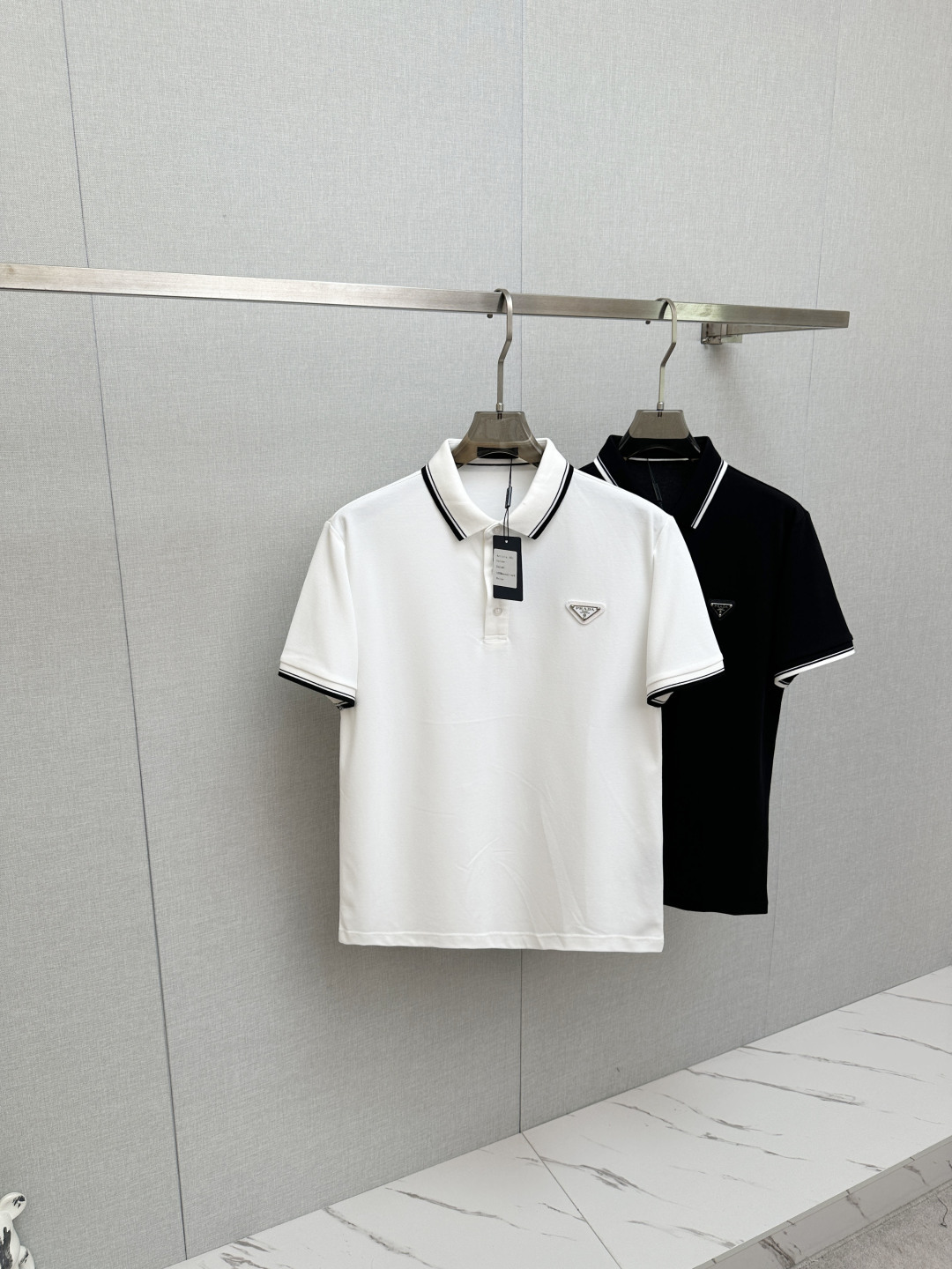 NO:841785,Prada. Prada SS26 new spring and summer classic metal triangle logo Polo shirt is presented in the simplest form, reflecting the casual and elegant style. The front chest is decorated with the brand's classic iconic triangle metal logo, which is very recognizable. It is an evergreen style, minimalist and versatile, made of piqué cotton fabric, the upper body is comfortable and breathable, high-quality fabric; color black, white, size M ~ XXXL,, prada, prada,19860909Prada.普拉达 SS26春夏新品经典金属三角形徽标Polo衫,以最简约的形式呈现,体现了休闲雅致风格,正面胸前饰有品牌经典标志性三角形金属标点缀超有辨识度,常青款、极简百搭,珠地棉面料,上身舒适透气、高品质面料； 颜色黑色、白色 尺码M～XXXL,,prada,prada,,Men's clothing